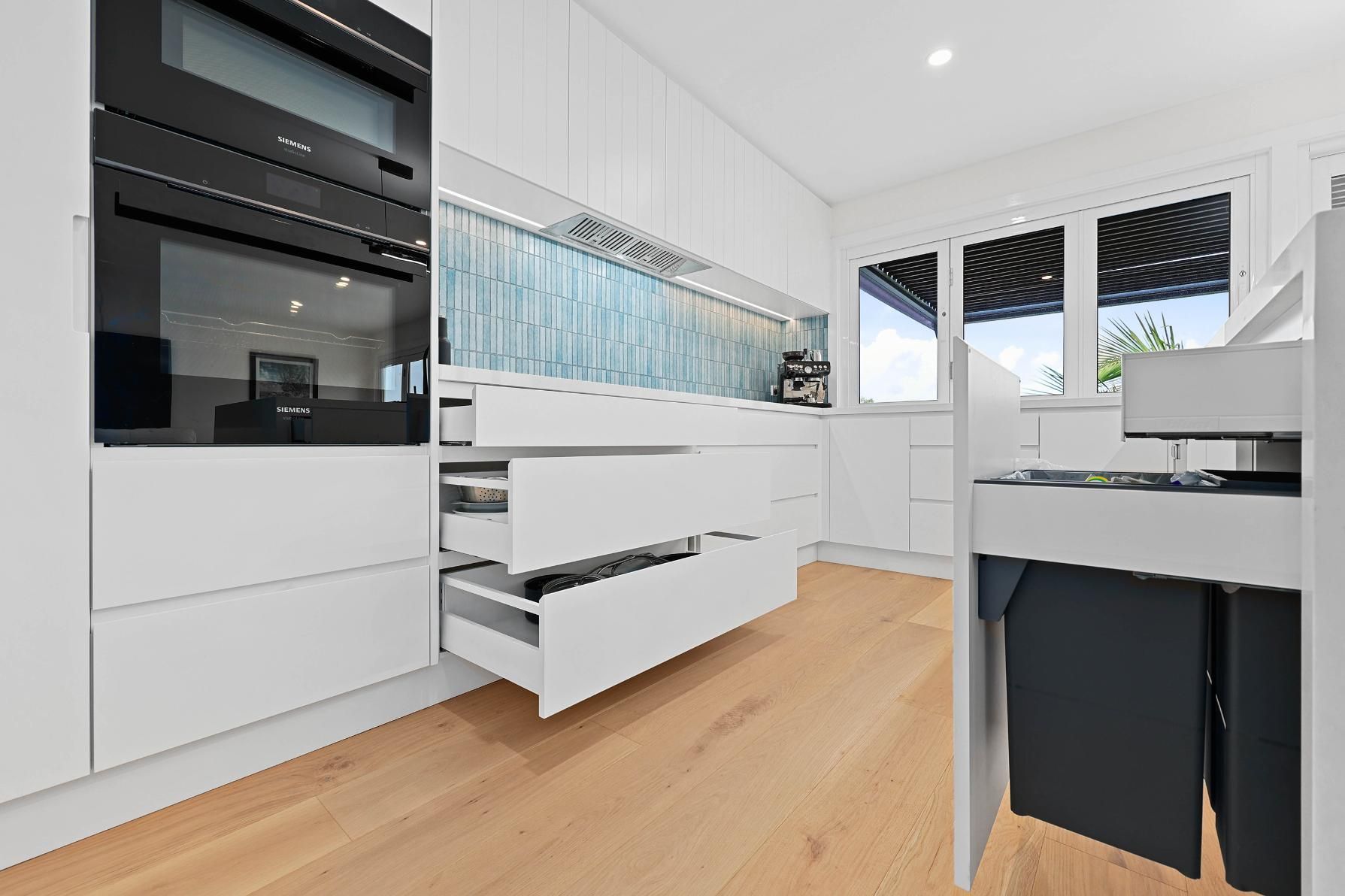 White Modern Kitchen with Built-In Oven, Drawers, and Light Wood Flooring — Above & Beyond Interiors Custom Joinery in North Curl Curl, NSW