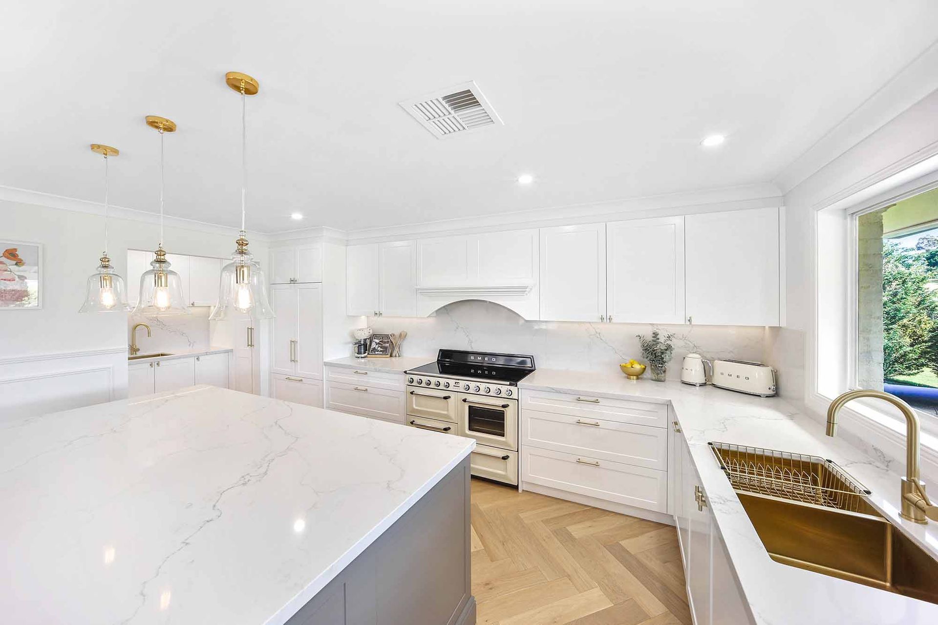 Modern kitchen with white cabinets, wooden floors and cream appliances — Above & Beyond Interiors in Smeaton Grange, NSW