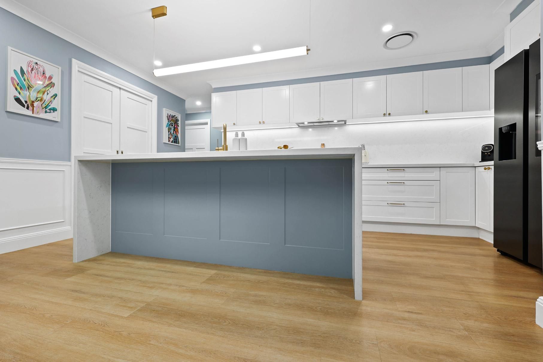 Modern Kitchen with Light Blue Island and White Cabinets, Light Wood Floors, and A Black Refrigerator — Above & Beyond Interiors Custom Joinery in Harrington Park, NSW