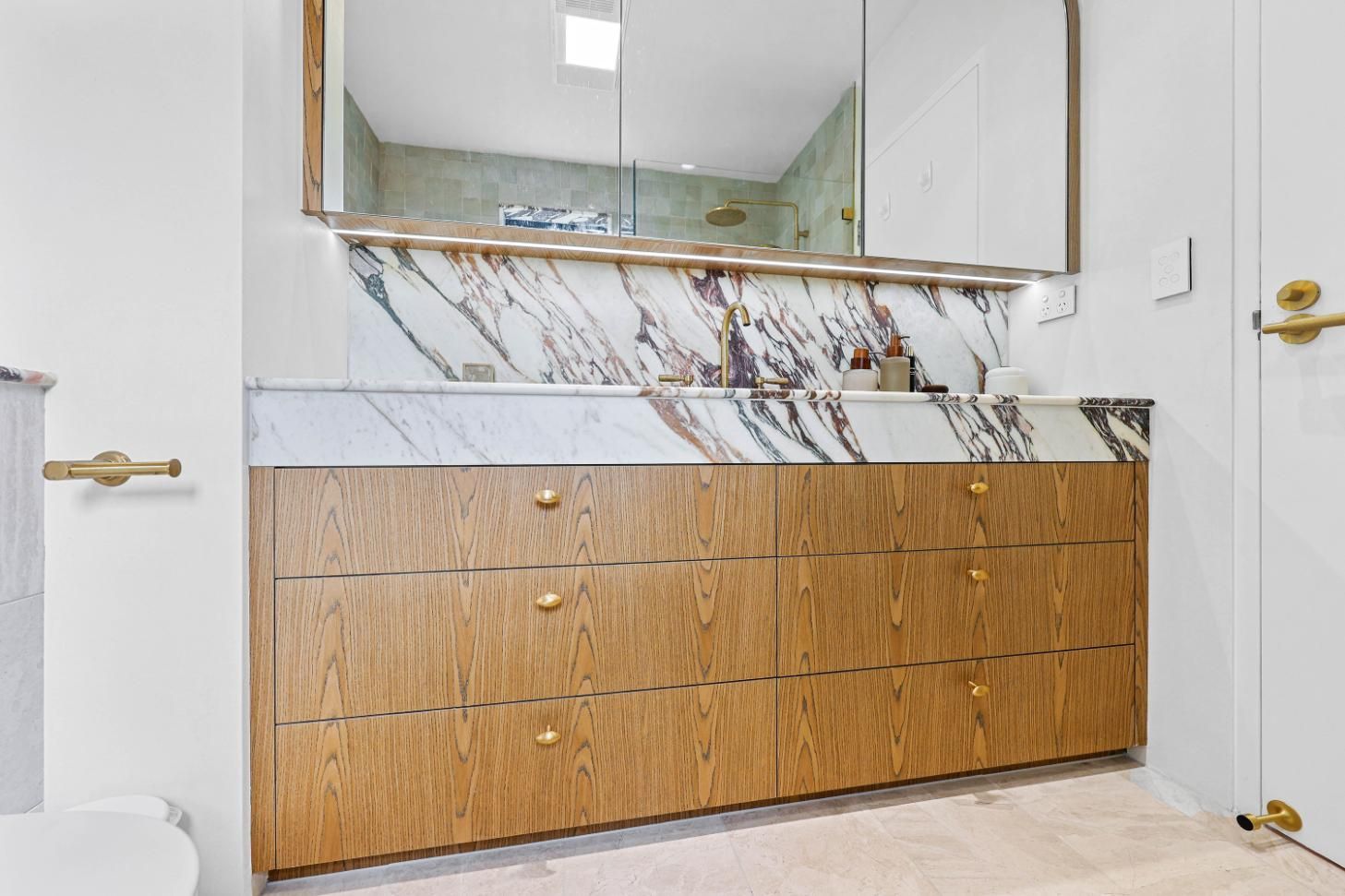 Bathroom with Wooden Vanity, Marble Backsplash, and Gold Accents — Above & Beyond Interiors Custom Joinery in Double Bay, NSW
