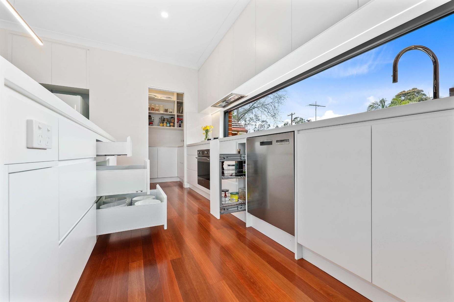 Modern White Kitchen with Open Drawers, Stainless Steel Appliances, and A View of The Outdoors — Above & Beyond Interiors Custom Joinery in Killara, NSW