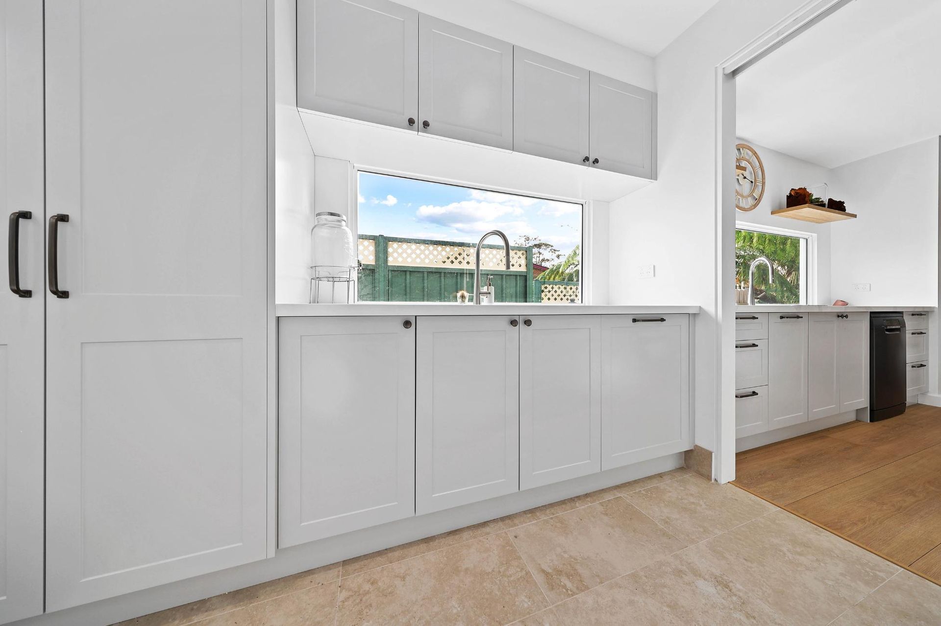 Grey and White Laundry Room with Cabinets, Sink, and Window Overlooking a Backyard — Above & Beyond Interiors Custom Joinery in Yowie Bay, NSW