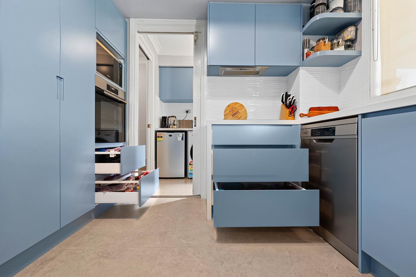 Blue Kitchen with Open Drawers, Dishwasher, and Built-In Oven. Light Beige Flooring — Above & Beyond Interiors Custom Joinery in Macquarie Fields, NSW
