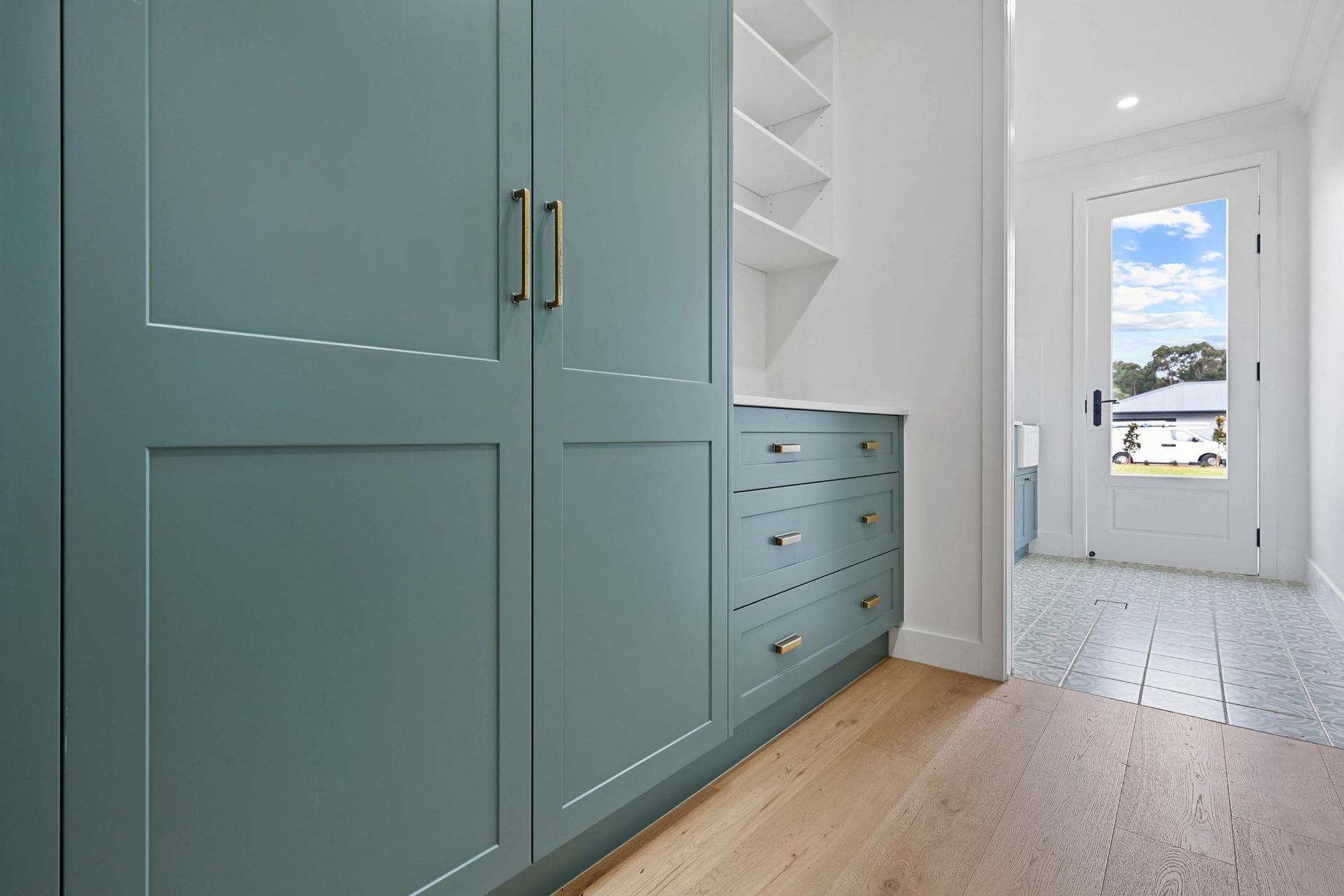 Blue Cabinets with Brass Hardware in A Hallway, Leading to An Exterior Door — Above & Beyond Interiors Custom Joinery in Appin, NSW