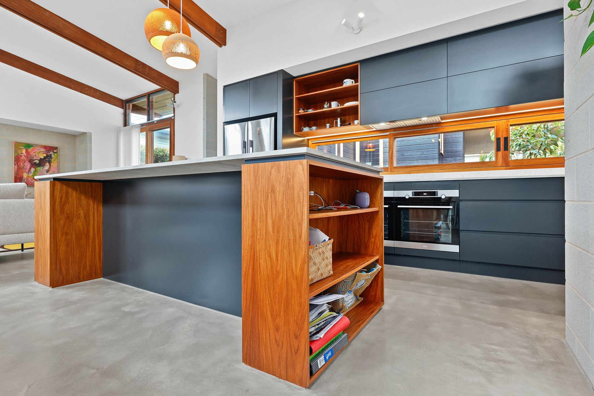 Modern kitchen with grey cabinets, wooden island and shelving, and concrete floor — Above & Beyond Interiors Custom Joinery in Bellambi, NSW
