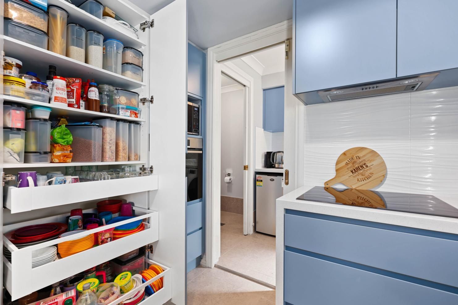 Blue Kitchen with Pantry Open; Door Leads to Small Appliances and A Refrigerator — Above & Beyond Interiors Custom Joinery in Macquarie Fields, NSW