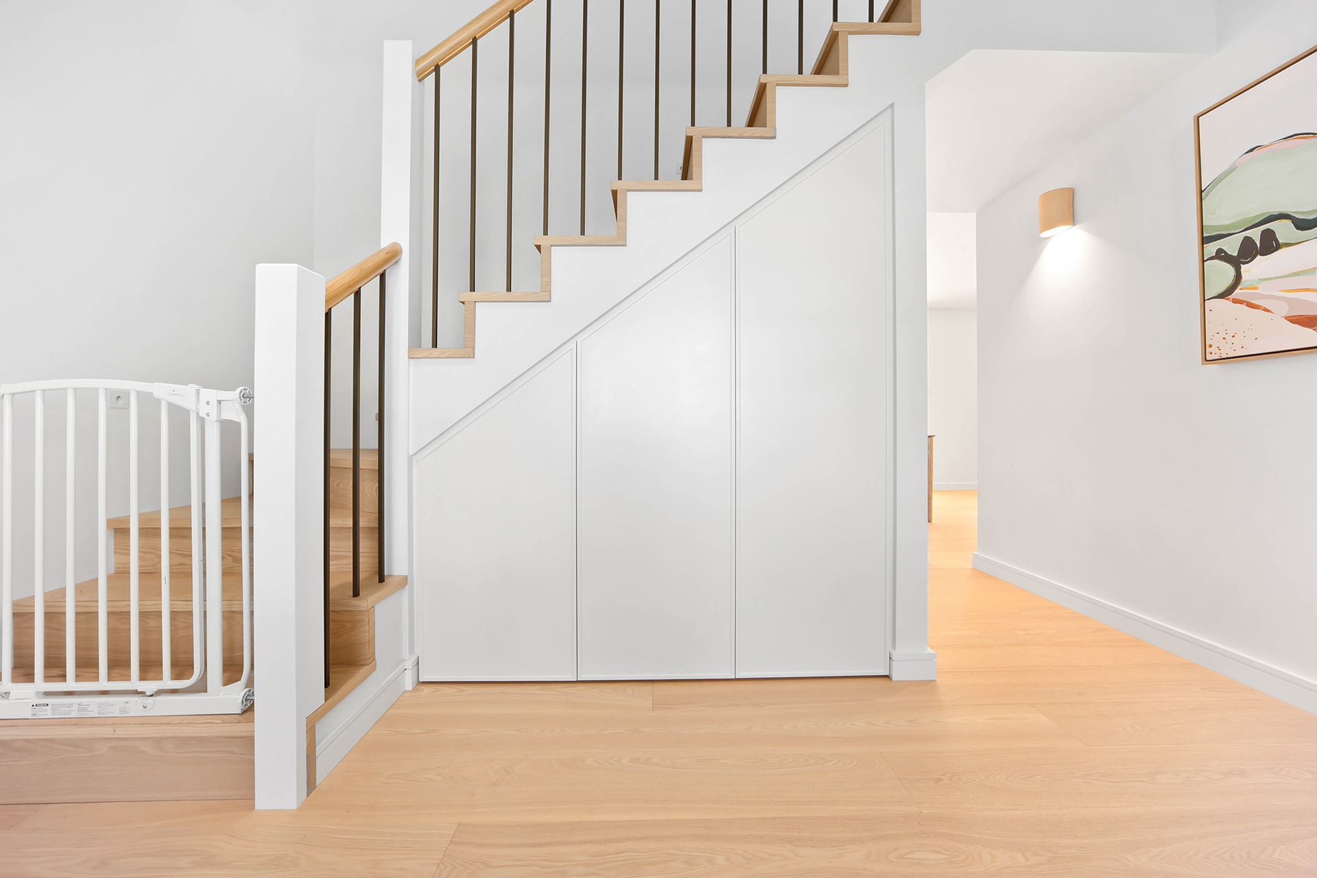Interior with stairs, light wood floors, white walls, and a child safety gate — Above & Beyond Interiors Custom Joinery in Bellambi, NSW