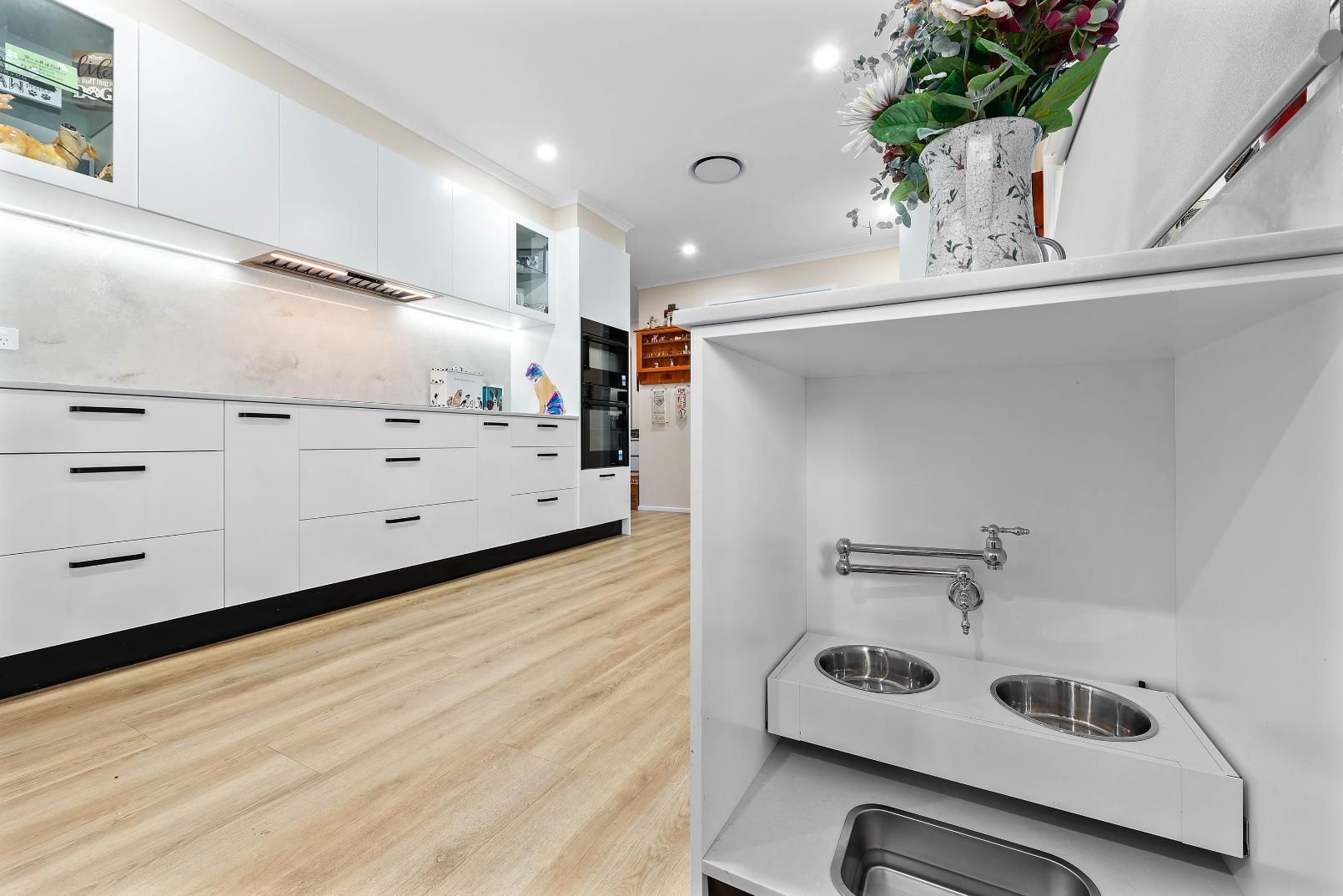 Modern White Kitchen with Pet Feeding Station. Bowls, Faucet, and Cabinets — Above & Beyond Interiors Custom Joinery in Bradbury, NSW
