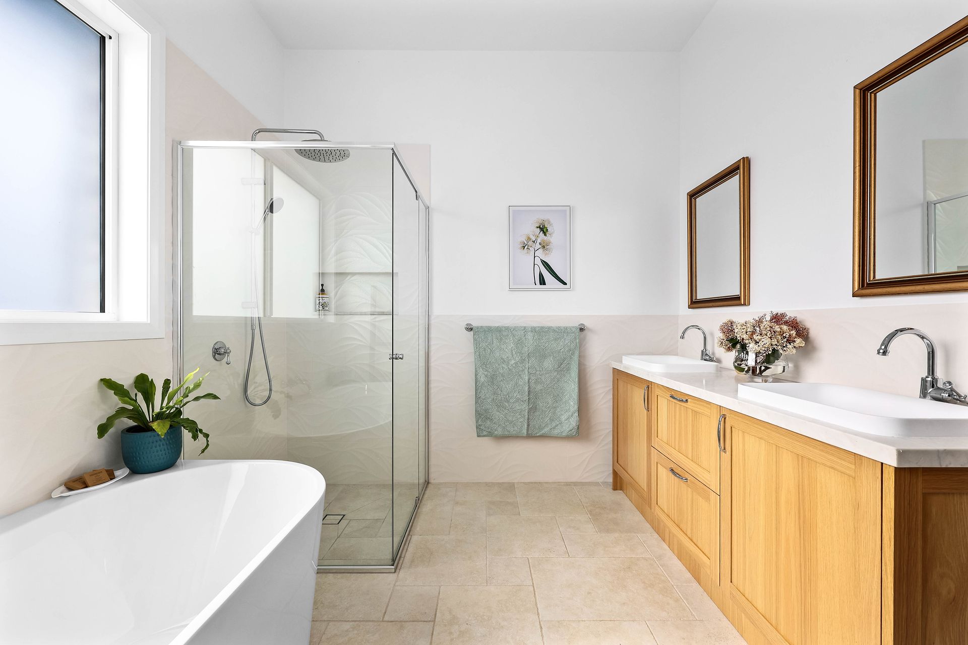 Bright bathroom: tub, glass shower, oak vanity with two sinks, two mirrors, light green towel, and window — Above & Beyond Interiors Custom Joinery in Bradbury, NSW