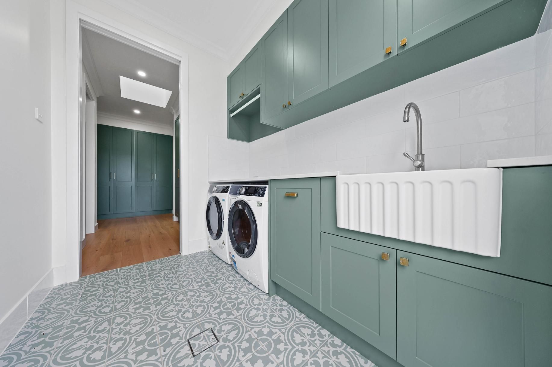 A Laundry Room with Green Cabinets, a White Farmhouse Sink, Patterned Floor Tiles, and A Washer/dryer — Above & Beyond Interiors Custom Joinery in Appin, NSW