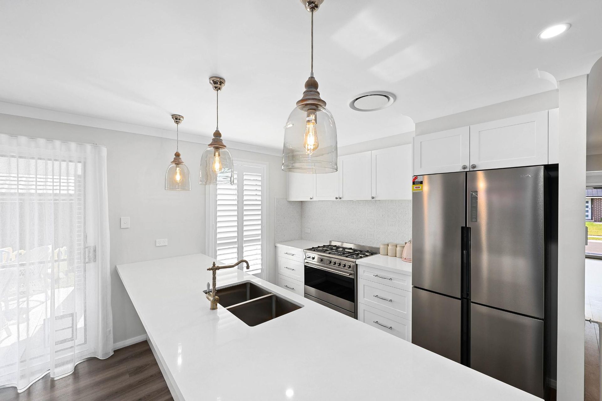 Modern White Kitchen with A Long Island, Stainless Steel Appliances, and Pendant Lights — Above & Beyond Interiors Custom Joinery in Thirlmere, NSW