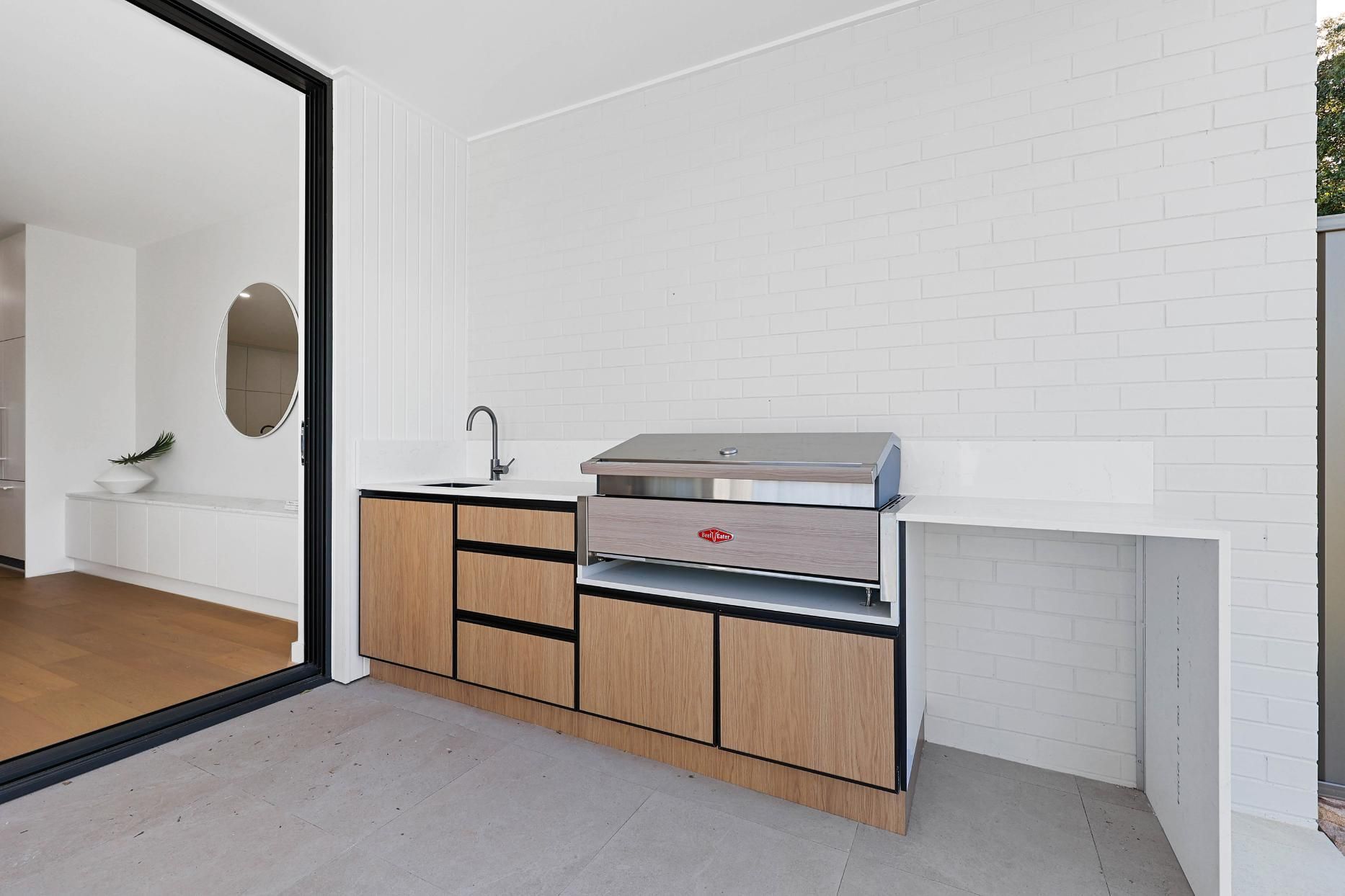 Outdoor Kitchen with Grill, Sink, and Cabinetry, with A White Brick Wall — Above & Beyond Interiors Custom Joinery in Thirroul, NSW
