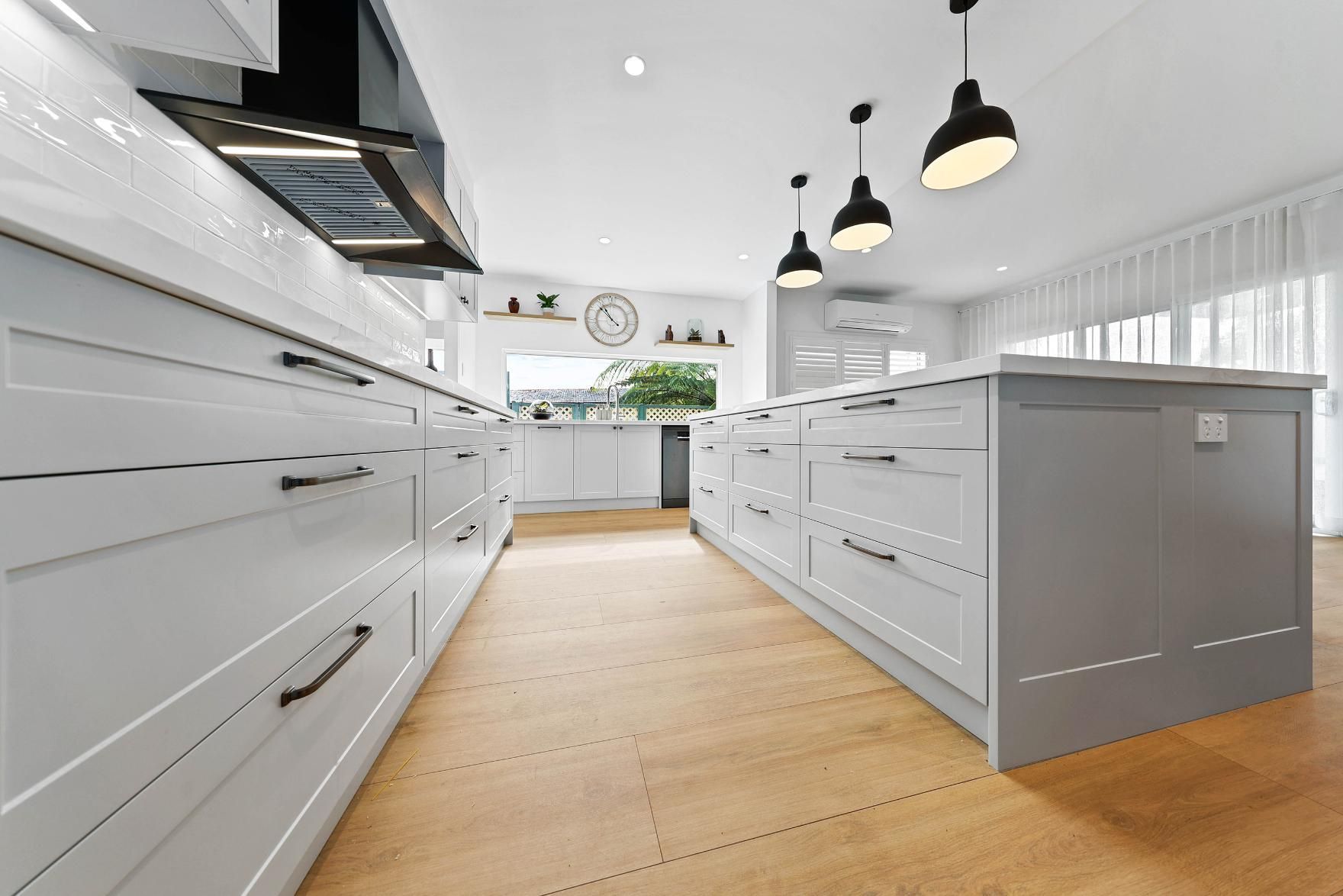 Modern White and Grey Kitchen with Light Wood Floor and Pendant Lights — Above & Beyond Interiors Custom Joinery in Yowie Bay, NSW
