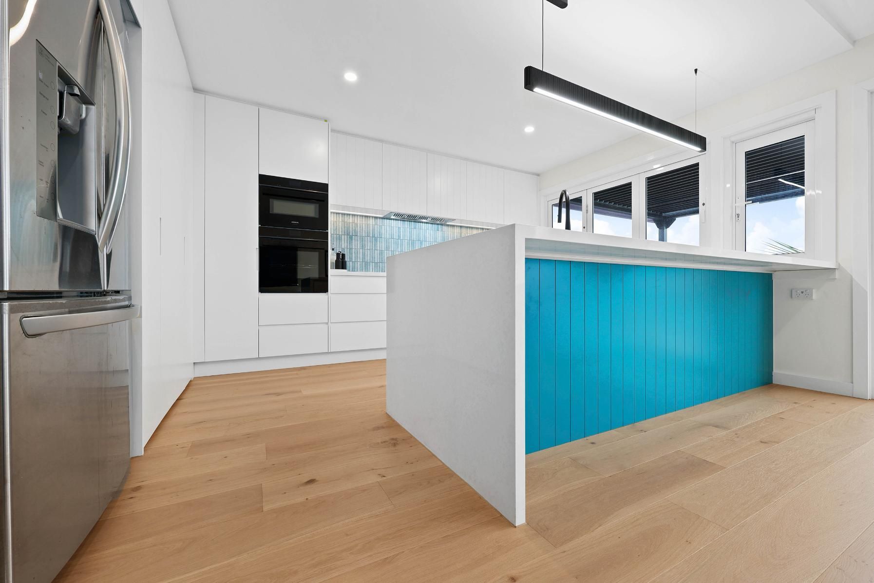 Modern Kitchen with White Cabinets and A Turquoise Island, Light Wood Floor — Above & Beyond Interiors Custom Joinery in North Curl Curl, NSW