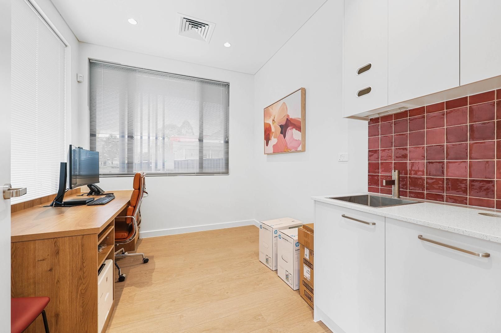 Office with Desk, Sink, and White Cabinets. Pink Tiles Above Sink. Light Tan Carpet — Above & Beyond Interiors Custom Joinery in Medical Centre, NSW