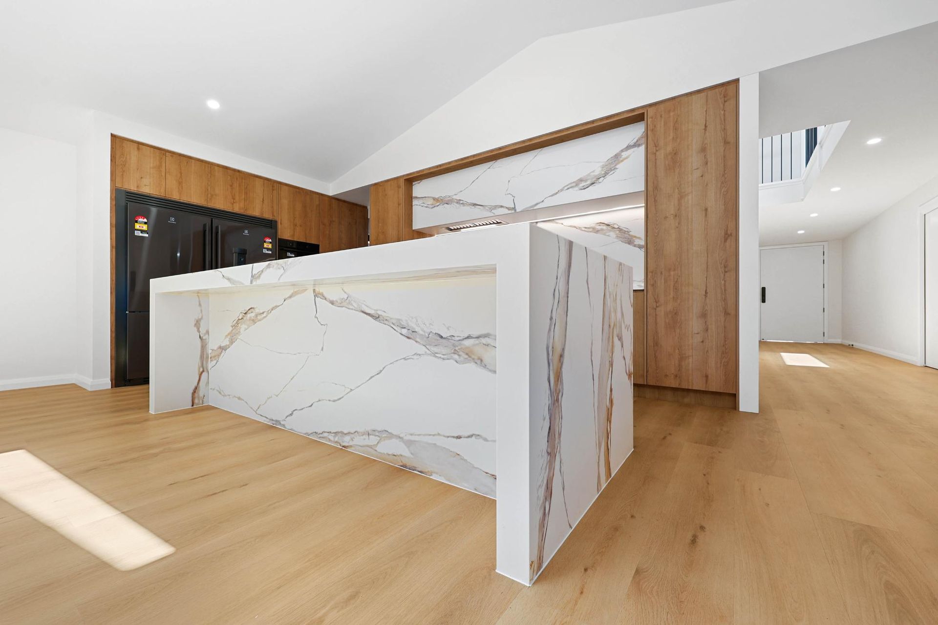 Modern Kitchen with Marble Island, Wood Accents, and Light Wood Flooring — Above & Beyond Interiors Custom Joinery in Abbortsbury, NSW