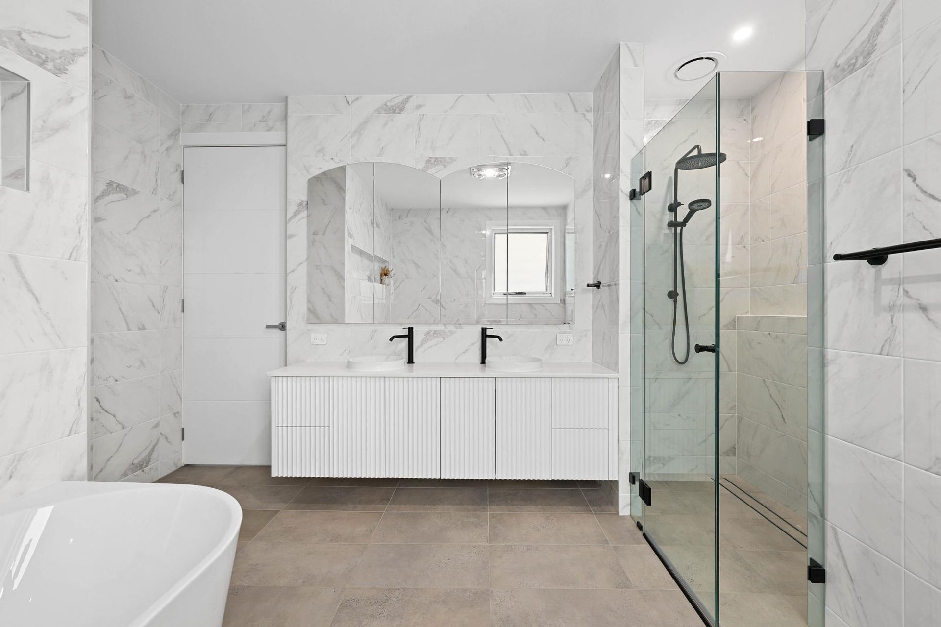 Modern white bathroom with marble-look walls, white vanity, glass shower, and freestanding tub — Above & Beyond Interiors Custom Joinery in Currans Hill, NSW