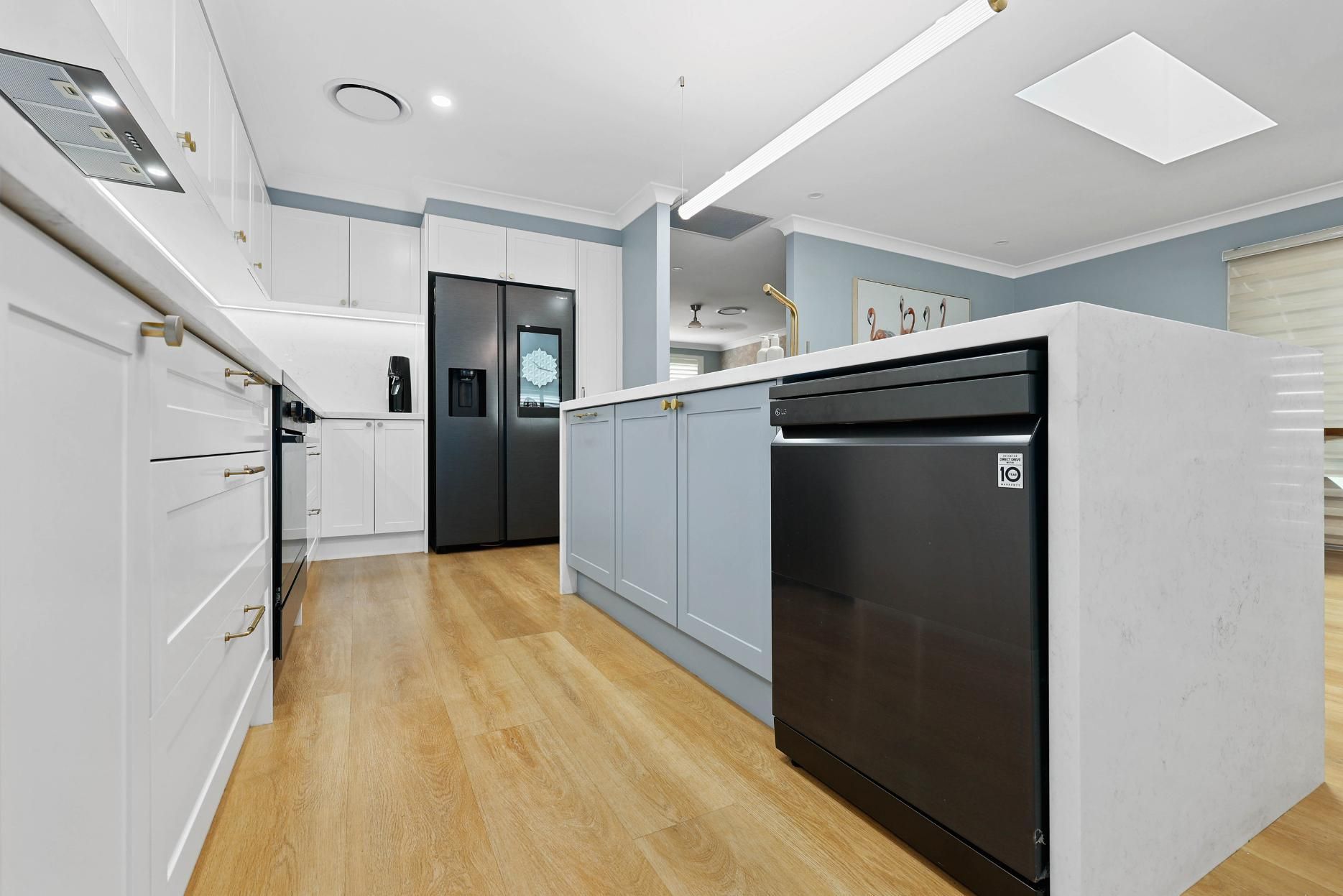 Modern Kitchen with White Cabinets, Grey Island, Black Appliances, and Wood Flooring — Above & Beyond Interiors Custom Joinery in Harrington Park, NSW