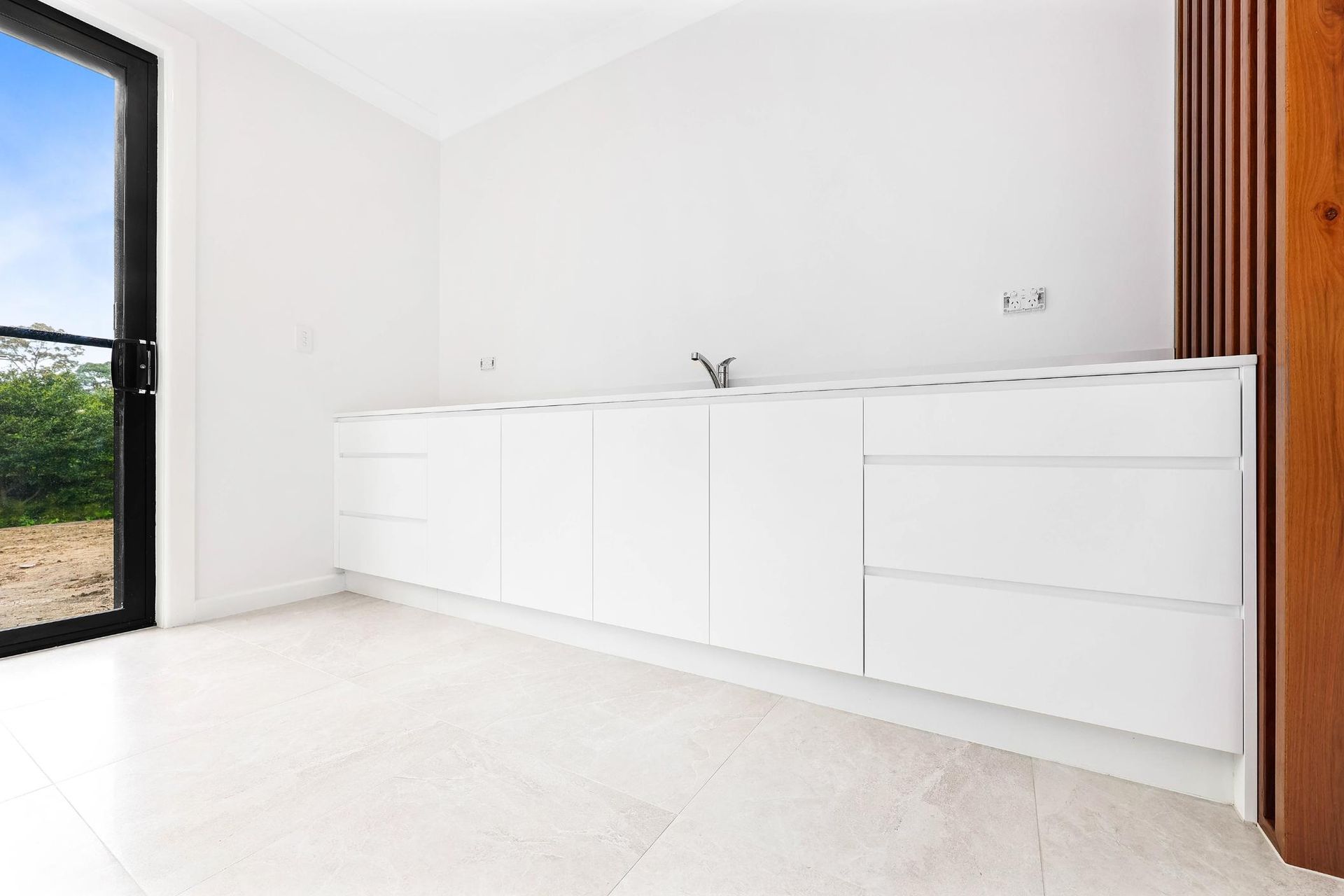 White Cabinets with A Sink and A Window in An Empty Room — Above & Beyond Interiors Custom Joinery in Killara, NSW