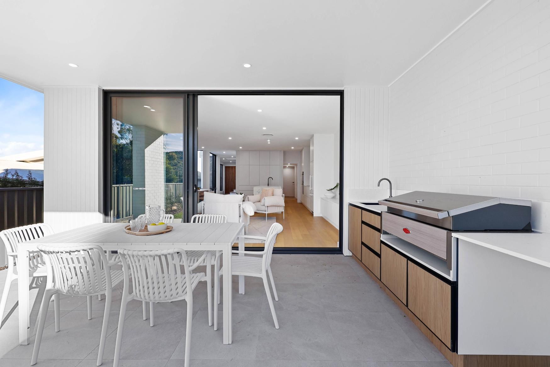 Outdoor Dining Area with White Table and Chairs, and A Built-In Grill and Sink — Above & Beyond Interiors Custom Joinery in Thirroul, NSW