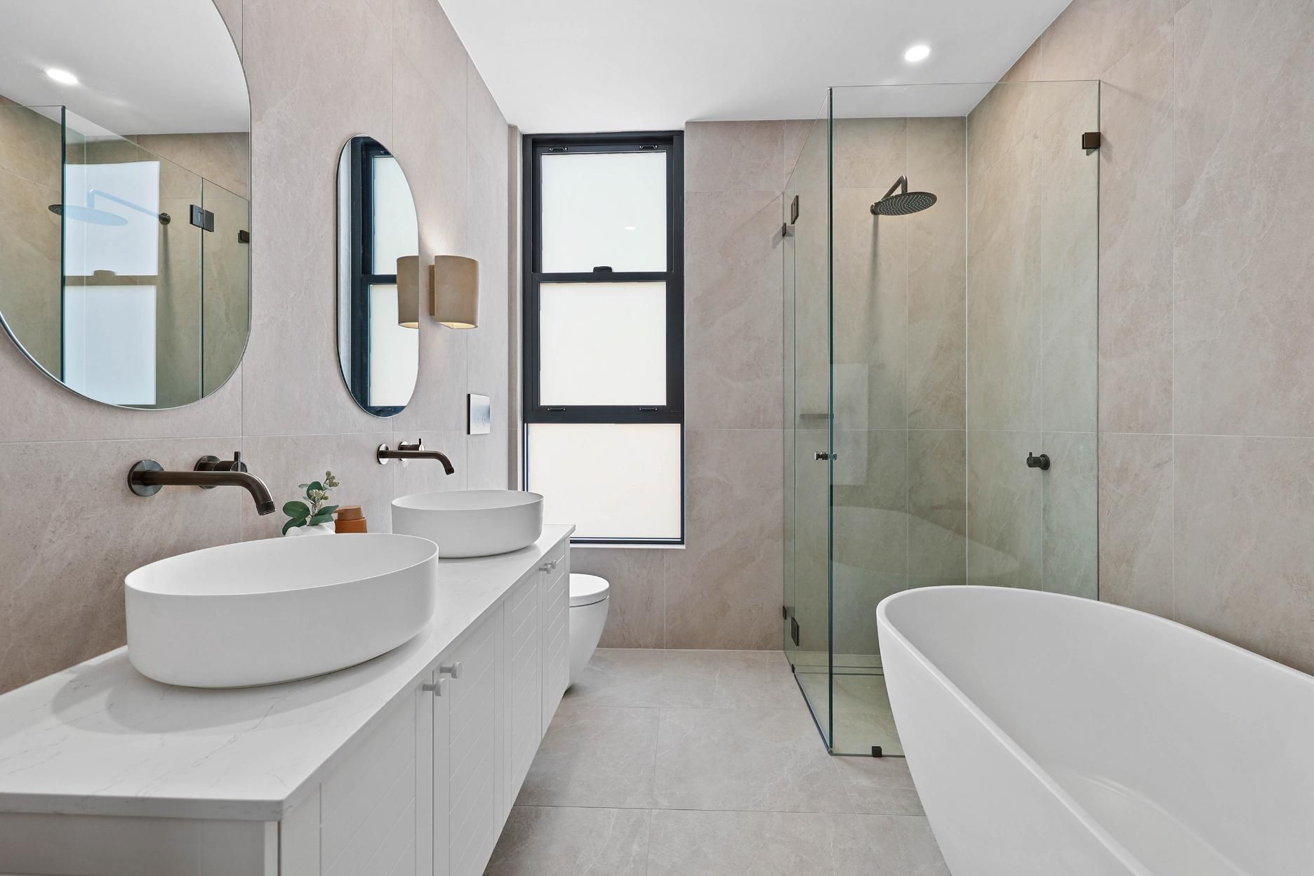 Modern Bathroom with White Vessel Sinks, Oval Mirrors, Shower, and Freestanding Tub — Above & Beyond Interiors Custom Joinery in Thirroul, NSW