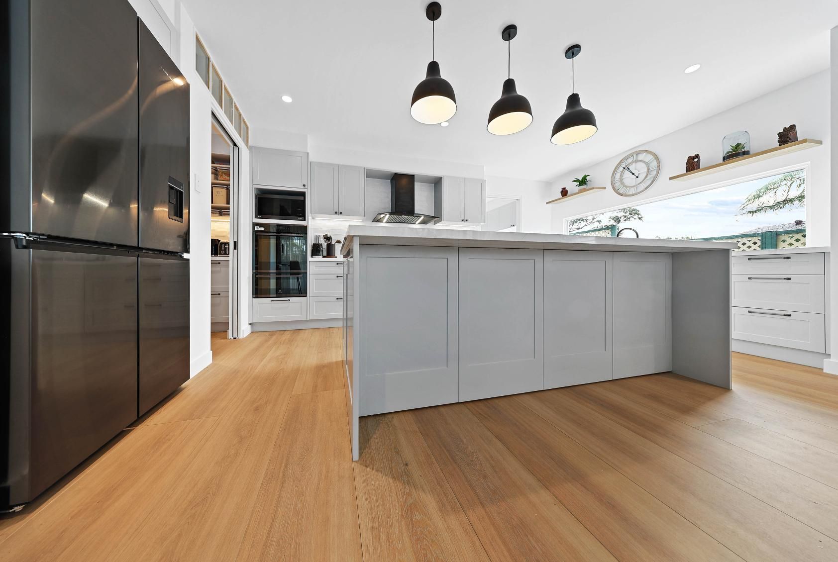 Modern Kitchen with Grey Cabinets, Island, and Hardwood Floors; Black Appliances and Pendant Lights — Above & Beyond Interiors Custom Joinery in Yowie Bay, NSW
