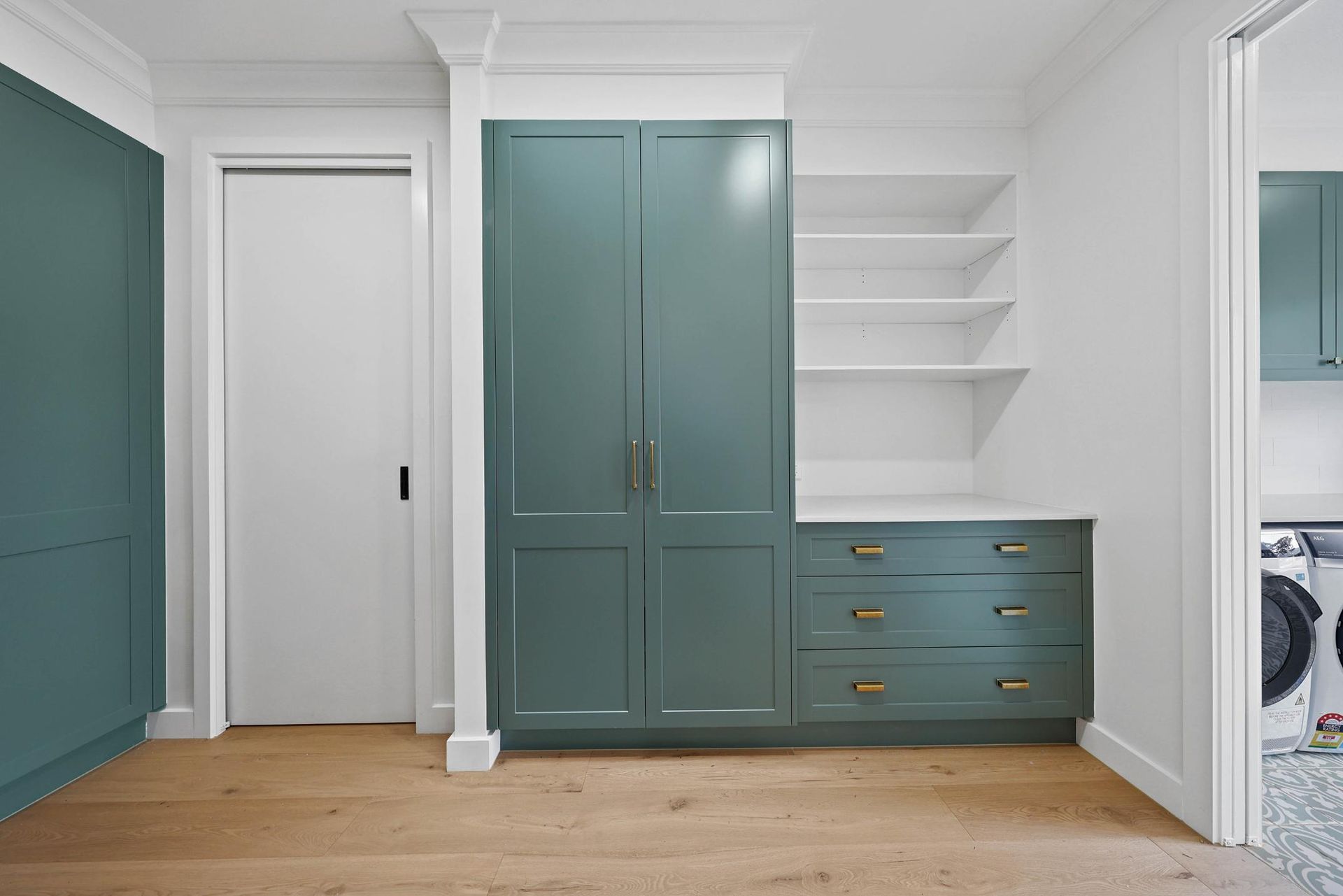A Laundry Room with Teal Cabinets, White Shelves, and A Wooden Floor — Above & Beyond Interiors Custom Joinery in Appin, NSW