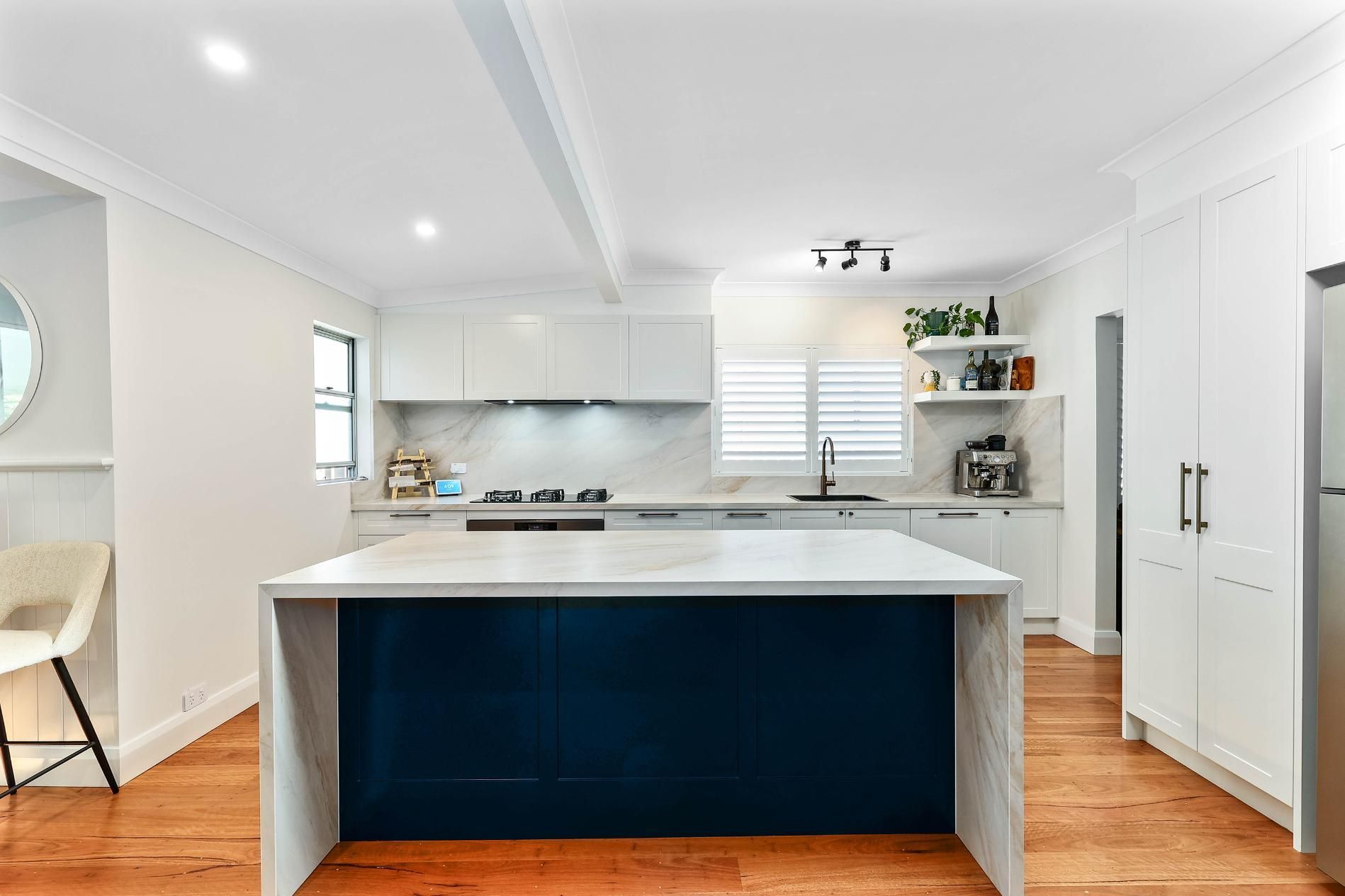 Modern White Kitchen with Navy Island and Wood Floors — Above & Beyond Interiors Custom Joinery in Bellambi, NSW