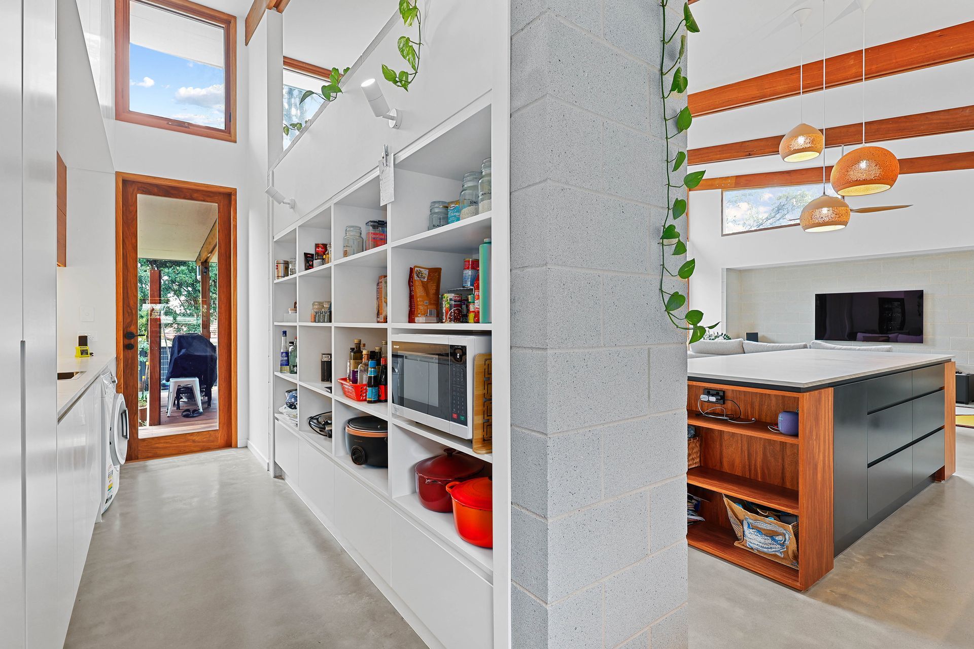 White kitchen with open shelving, a wood-trimmed island, and a doorway to a backyard — Above & Beyond Interiors Custom Joinery in Bellambi, NSW