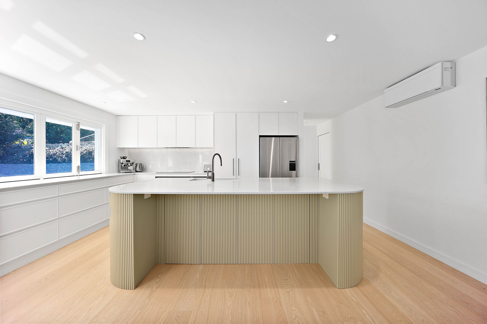 Modern white kitchen with island and light wood floors — Above & Beyond Interiors Custom Joinery in Bellambi, NSW