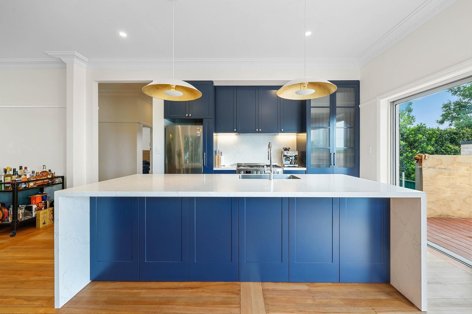 Blue Kitchen Island with White Countertop; Blue Cabinets, Gold Pendant Lights; Wooden Floors — Above & Beyond Interiors Custom Joinery in Lilyfield, NSW