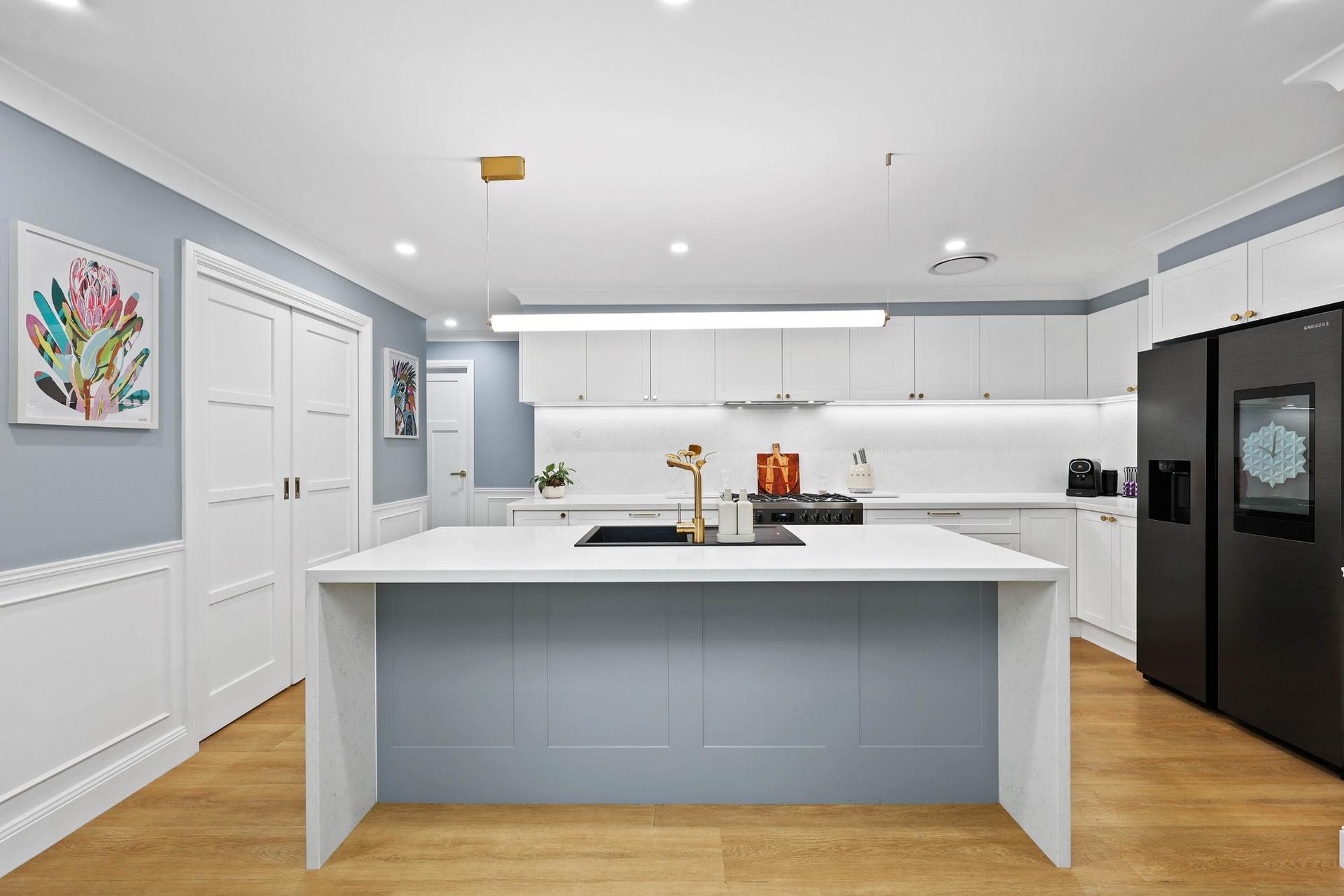 Modern Kitchen with White Cabinets, Blue Island, Black Appliances, and Wood Floors — Above & Beyond Interiors Custom Joinery in Harrington Park, NSW