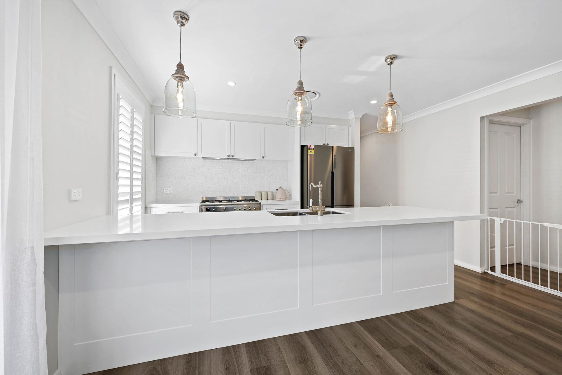 Modern White Kitchen with Island, Stainless Steel Appliances, and Pendant Lights — Above & Beyond Interiors Custom Joinery in Thirlmere, NSW