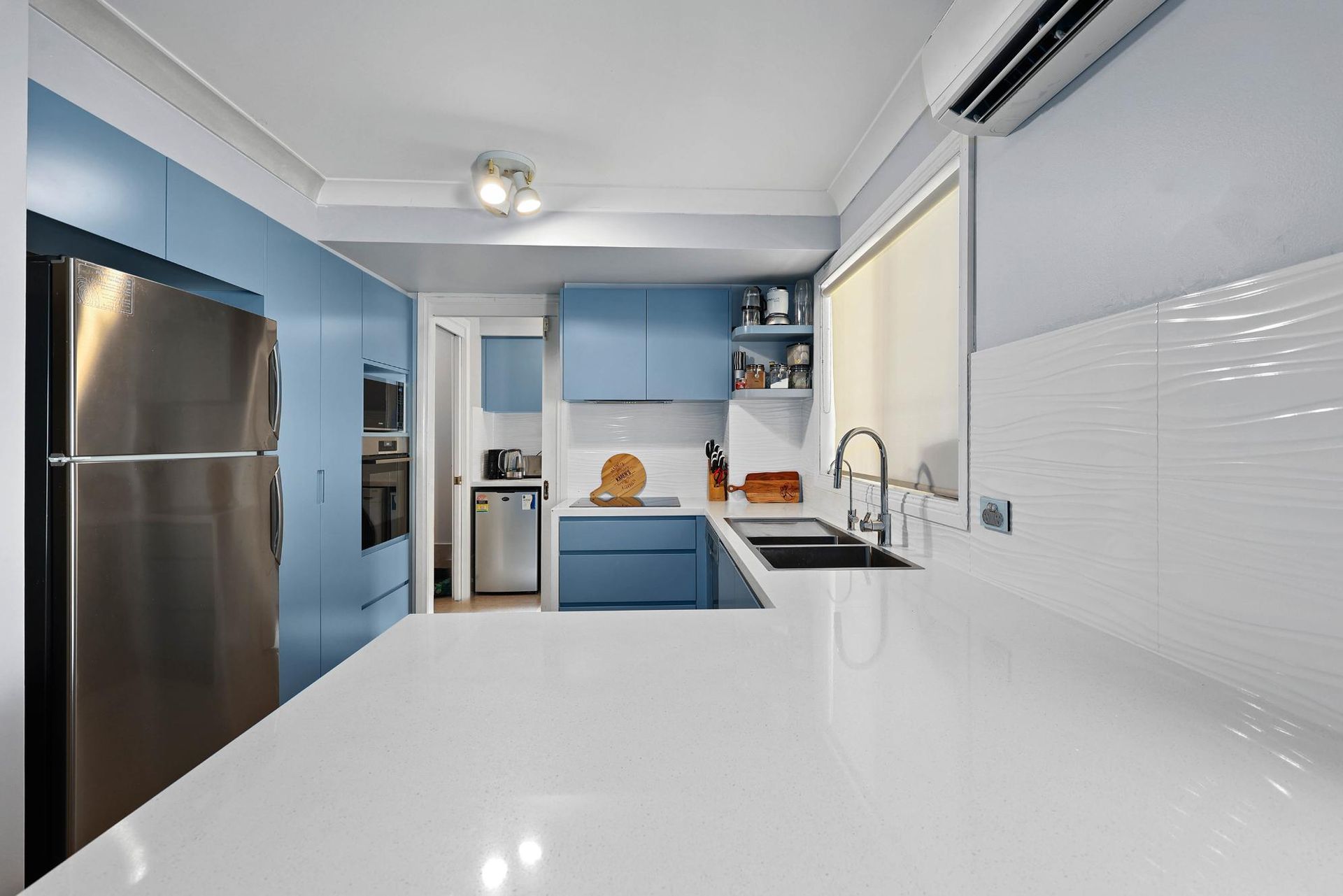 Blue and White Kitchen with Stainless Steel Refrigerator and White Countertop — Above & Beyond Interiors Custom Joinery in Macquarie Fields, NSW