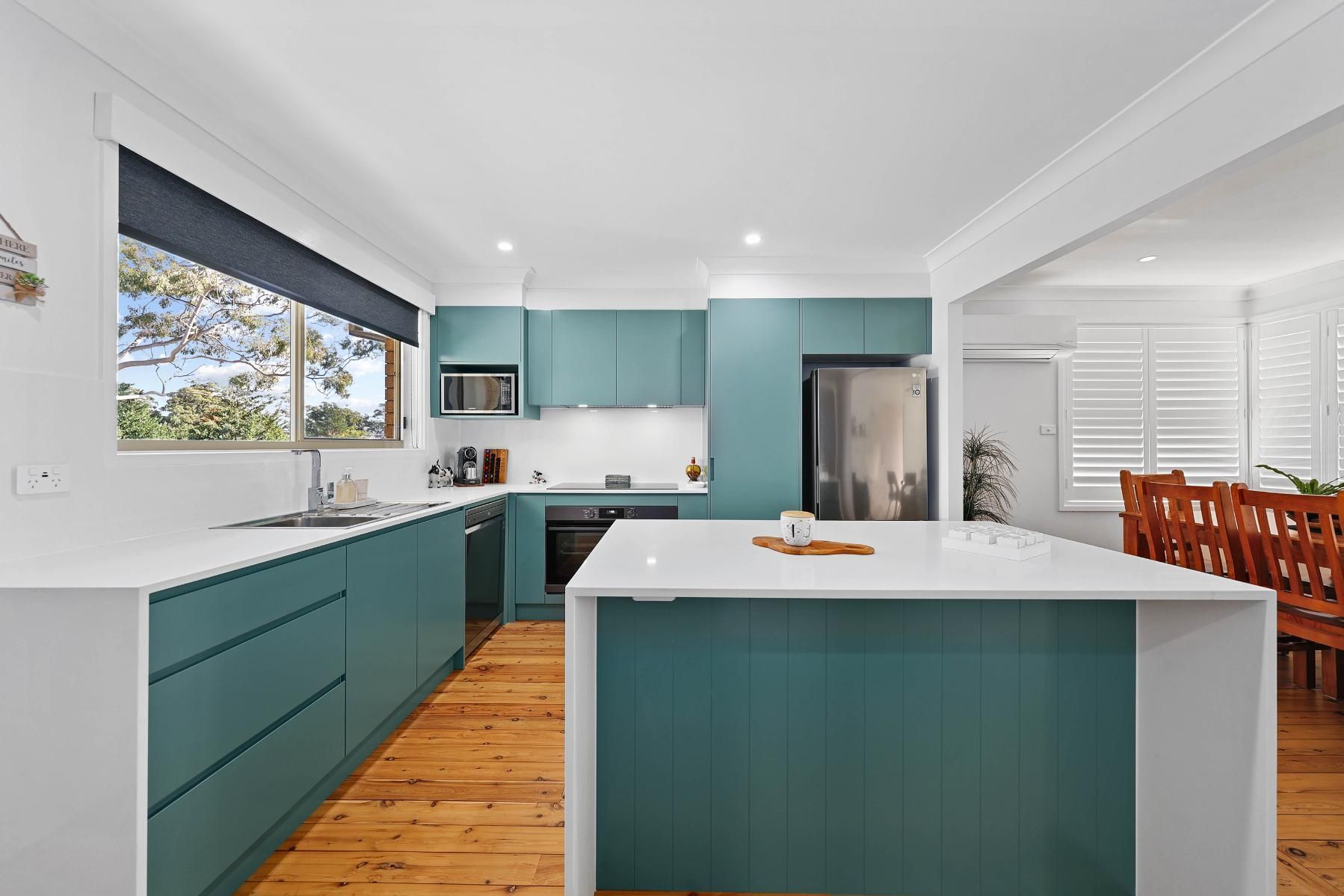 Teal Kitchen with White Countertops, Island, and Hardwood Floors; Open to A Dining Room with Shutters — Above & Beyond Interiors Custom Joinery in Bradbury, NSW