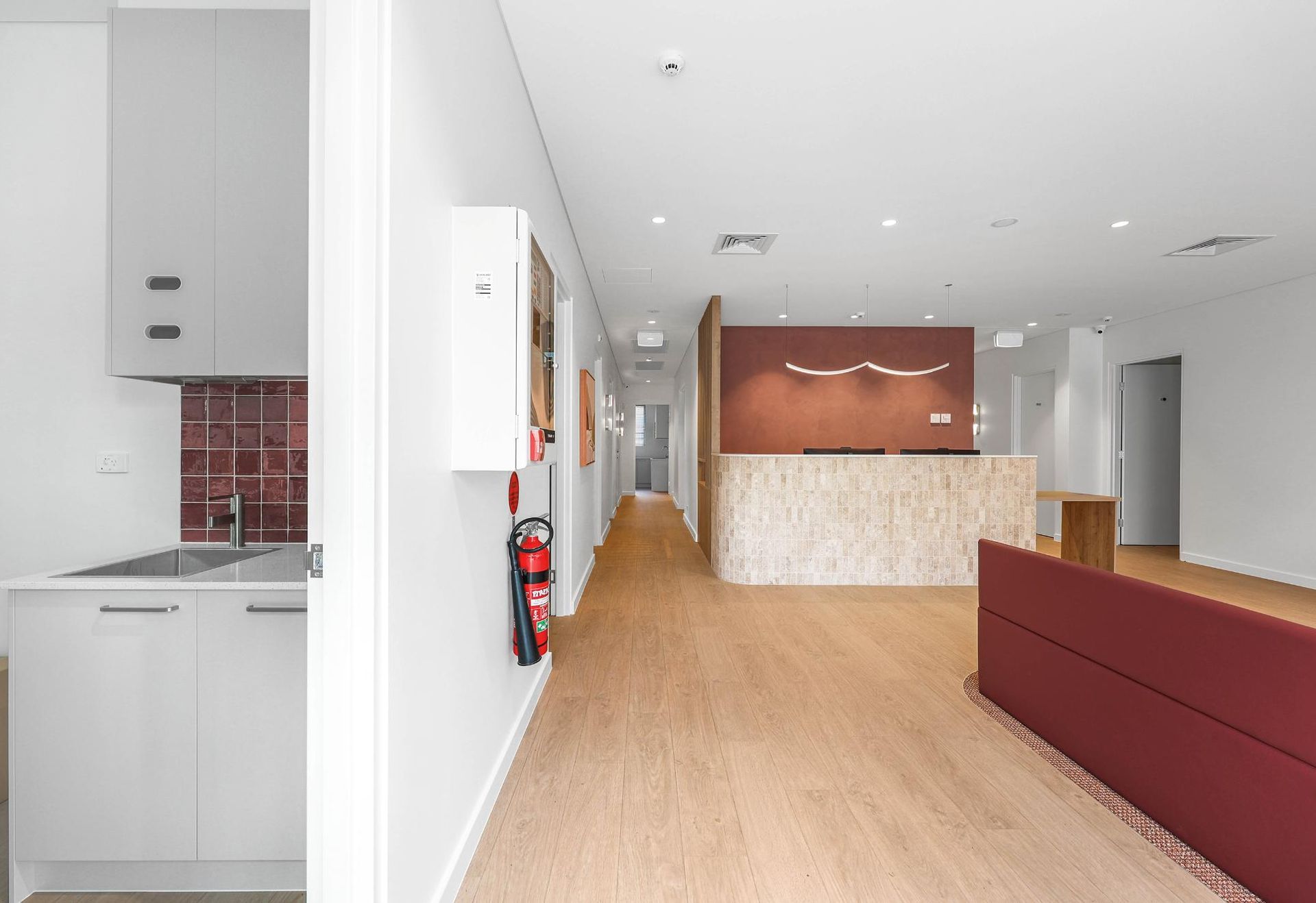Office Interior with A Reception Desk, Red Accent Wall, and Kitchenette — Above & Beyond Interiors Custom Joinery in Medical Centre, NSW