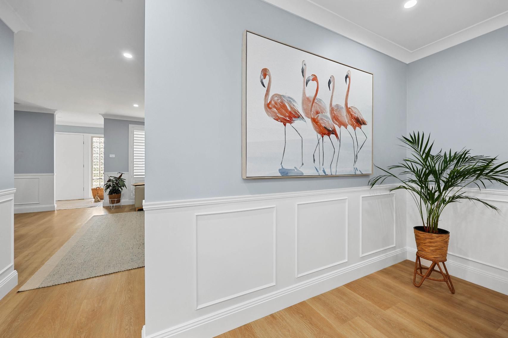 A Brightly Lit Entryway with A Flamingo Painting, Wood Floors, and A Potted Plant — Above & Beyond Interiors Custom Joinery in Harrington Park, NSW
