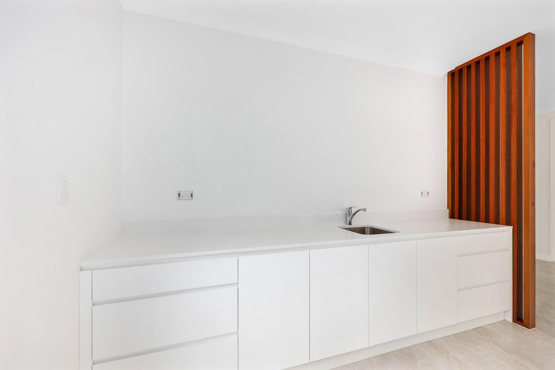 White Kitchen Counter with Sink, Cabinets, and Wood Slat Divider — Above & Beyond Interiors Custom Joinery in Killara, NSW