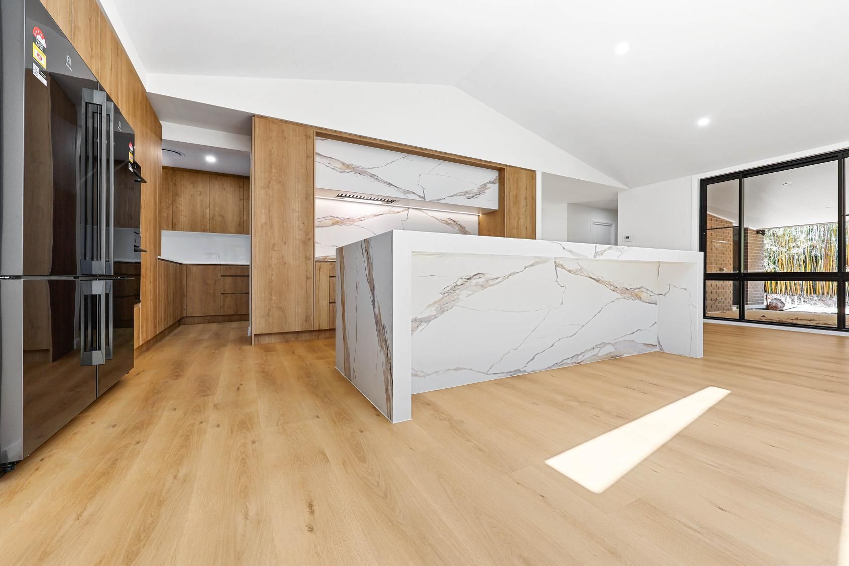 Modern Kitchen with White Marble Island and Wooden Cabinets, Natural Light from Large Windows — Above & Beyond Interiors Custom Joinery in Abbortsbury, NSW