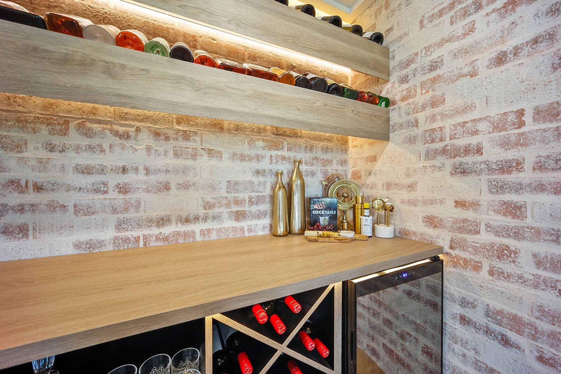 Wine bar with exposed brick walls, wooden shelves holding wine bottles, and a counter with a cooler — Above & Beyond Interiors Custom Joinery in Bellambi, NSW