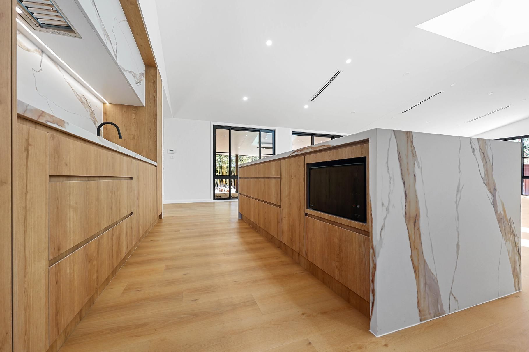 Modern Kitchen with Light Wood Cabinets, a Marble Island, and Light-Colored Floors — Above & Beyond Interiors Custom Joinery in Abbortsbury, NSW