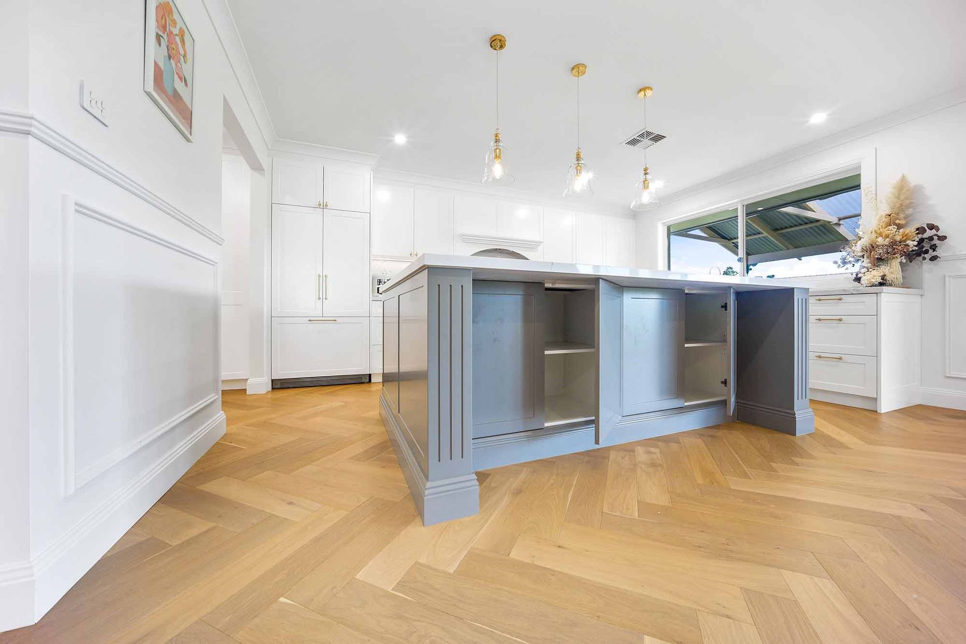 Modern kitchen with grey island, wood flooring, and white cabinets — Above & Beyond Interiors Custom Joinery in Bellambi, NSW