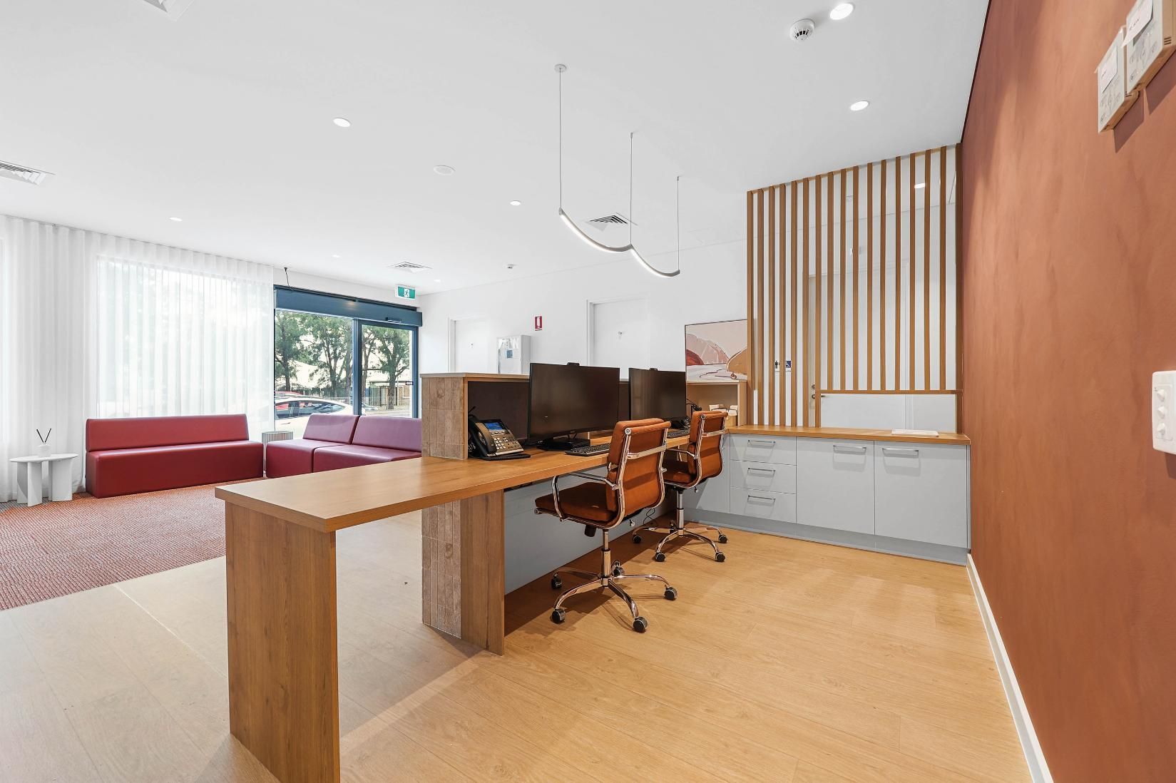 Reception Area with Desk, Chairs, and Waiting Area with Red and Purple Sofas — Above & Beyond Interiors Custom Joinery in Medical Centre, NSW
