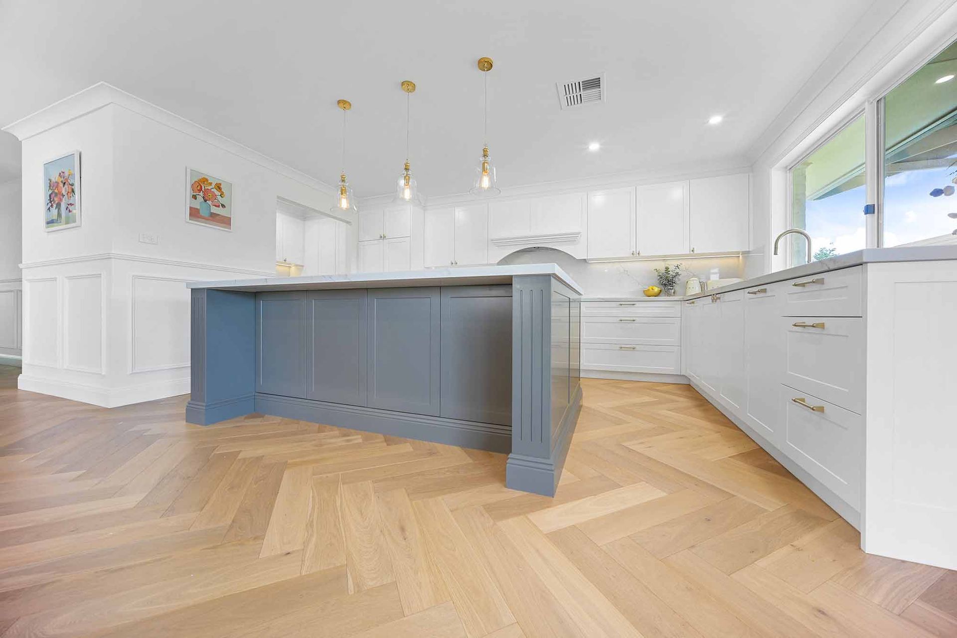 Modern kitchen with grey island, white cabinets, and herringbone wood floor — Above & Beyond Interiors Custom Joinery in Bellambi, NSW