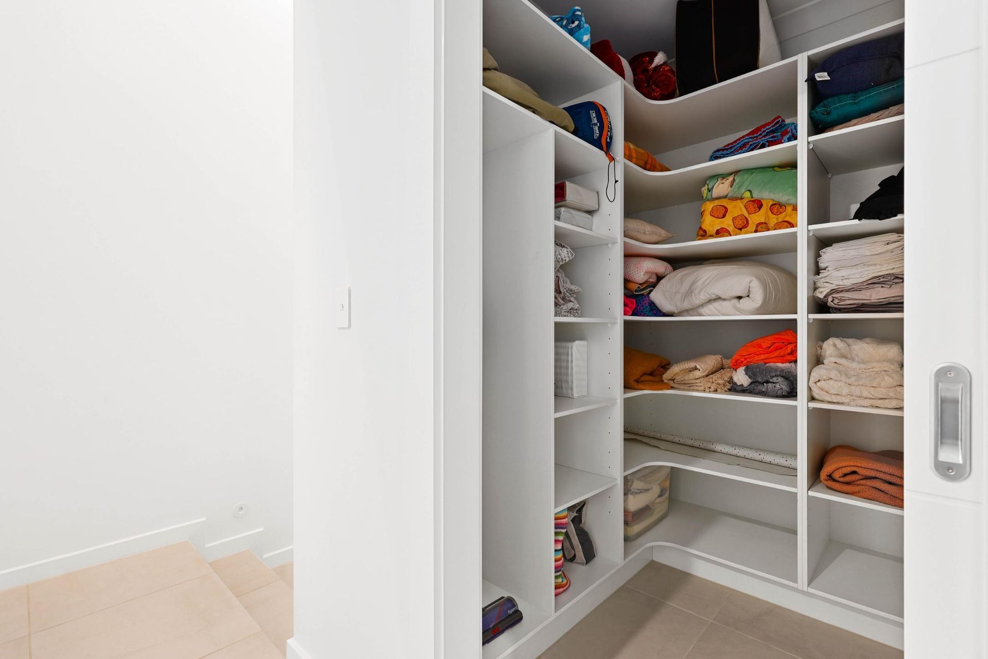 White Walk-In Closet Filled with Neatly Folded Clothes and Accessories, on A Beige Carpet — Above & Beyond Interiors Custom Joinery in Currans Hill, NSW