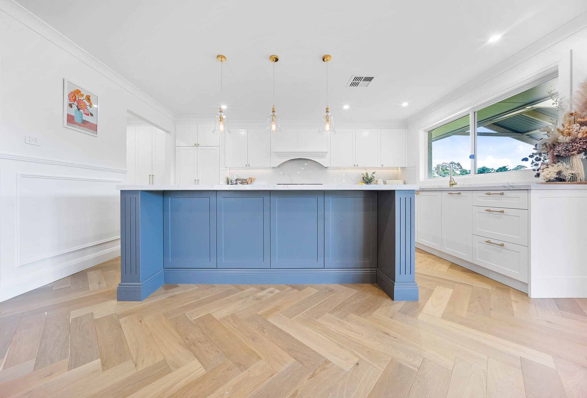 Blue kitchen island with white countertop and gold pendant lights. Herringbone wood floors — Above & Beyond Interiors Custom Joinery in Bellambi, NSW