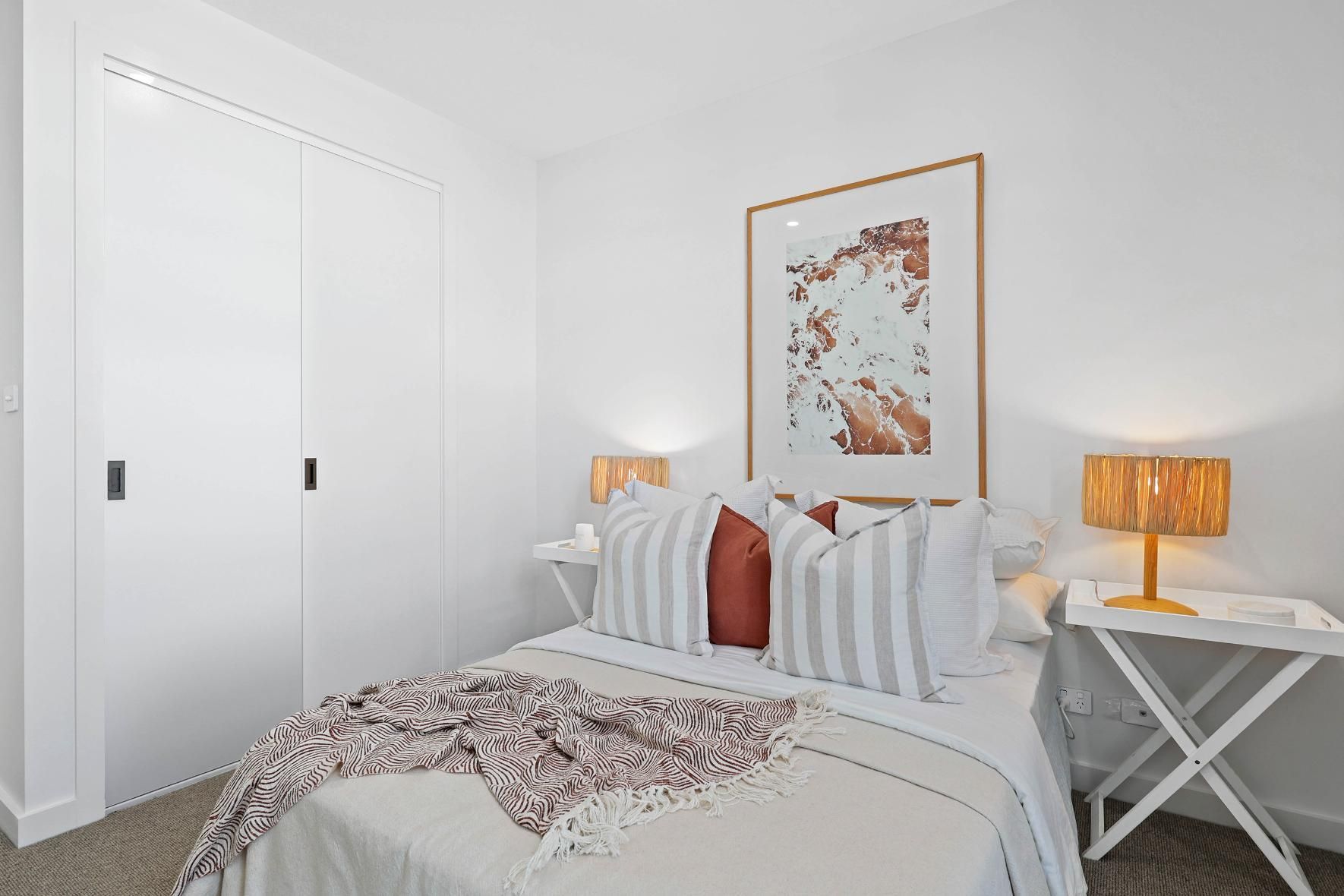 White Bedroom with Bed, Artwork, Bedside Tables, and Sliding Closet Doors — Above & Beyond Interiors Custom Joinery in Thirroul, NSW