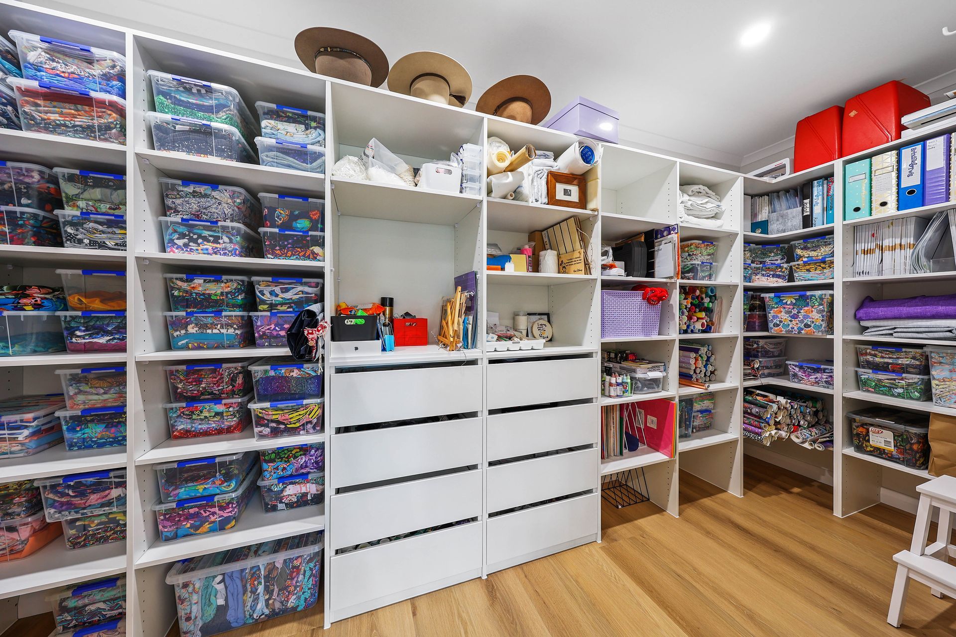 White closet with built-in shelves and drawers filled with containers, toys, and files; hats on top — Above & Beyond Interiors Custom Joinery in Bellambi, NSW