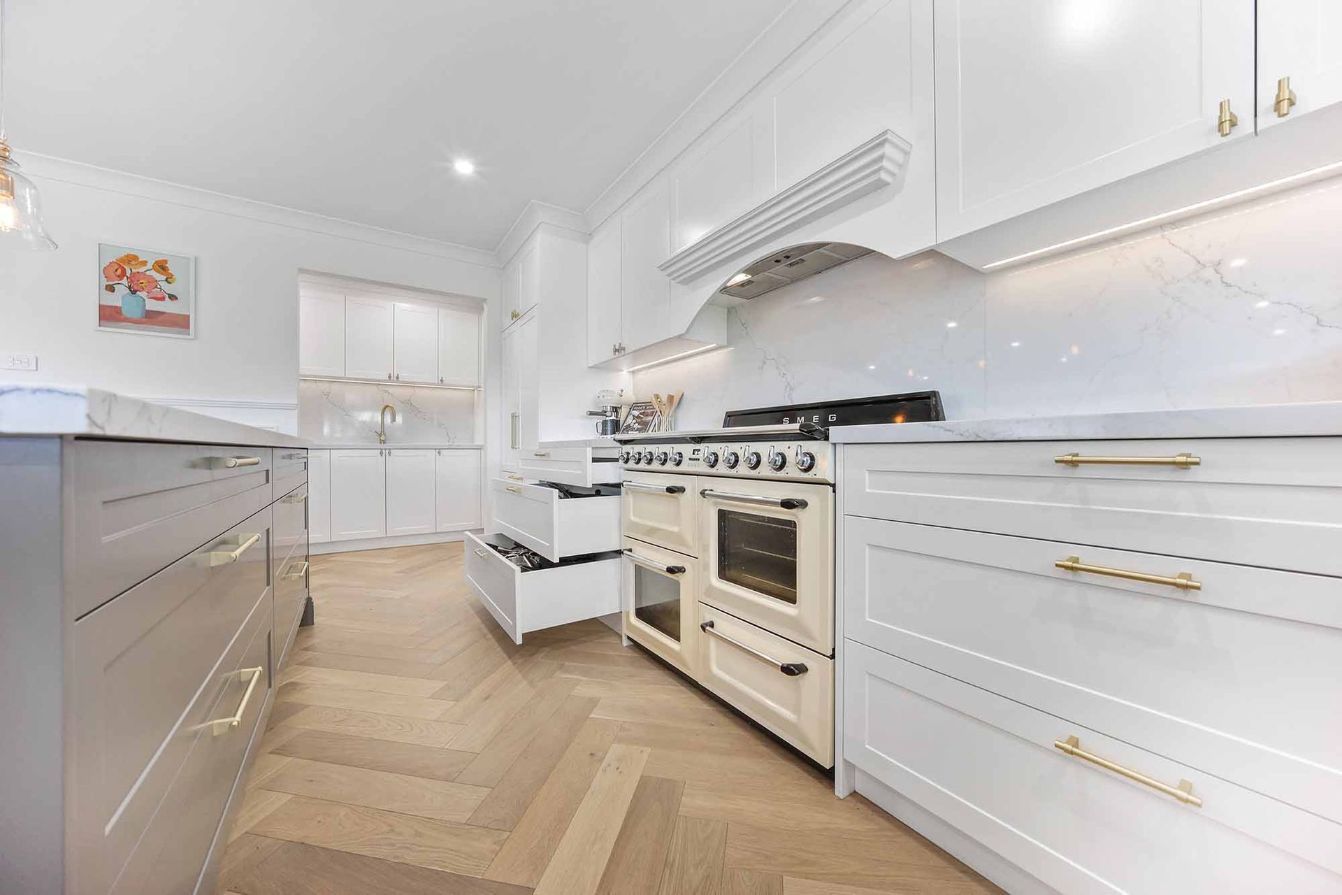 White kitchen with wood floors, marble countertops, and a cream-colored range — Above & Beyond Interiors Custom Joinery in Bellambi, NSW