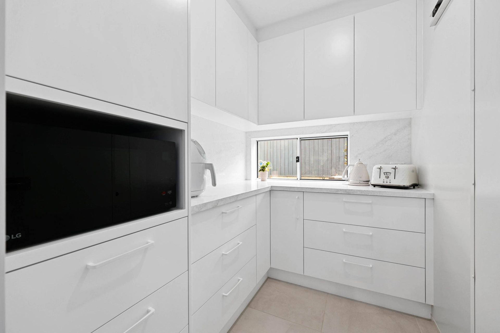 White, Minimalist Kitchen with Built-In Microwave, Drawers, and Small Window — Above & Beyond Interiors Custom Joinery in Currans Hill, NSW